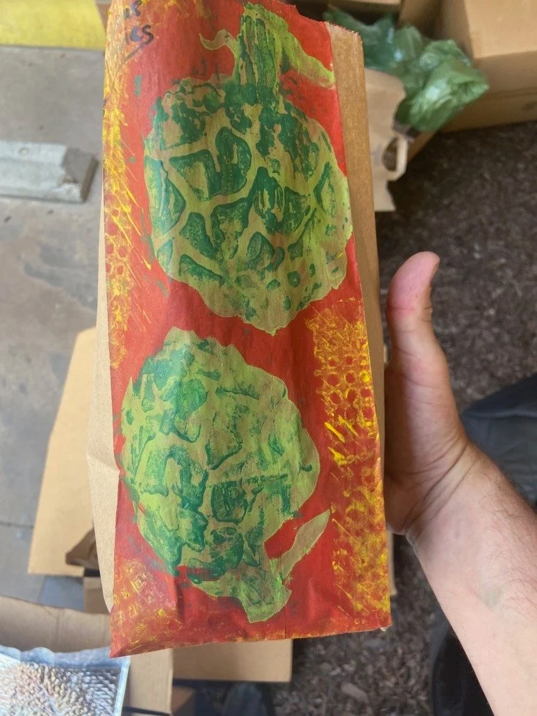 A hand holding a piece of paper with green lettuce print on a red background.