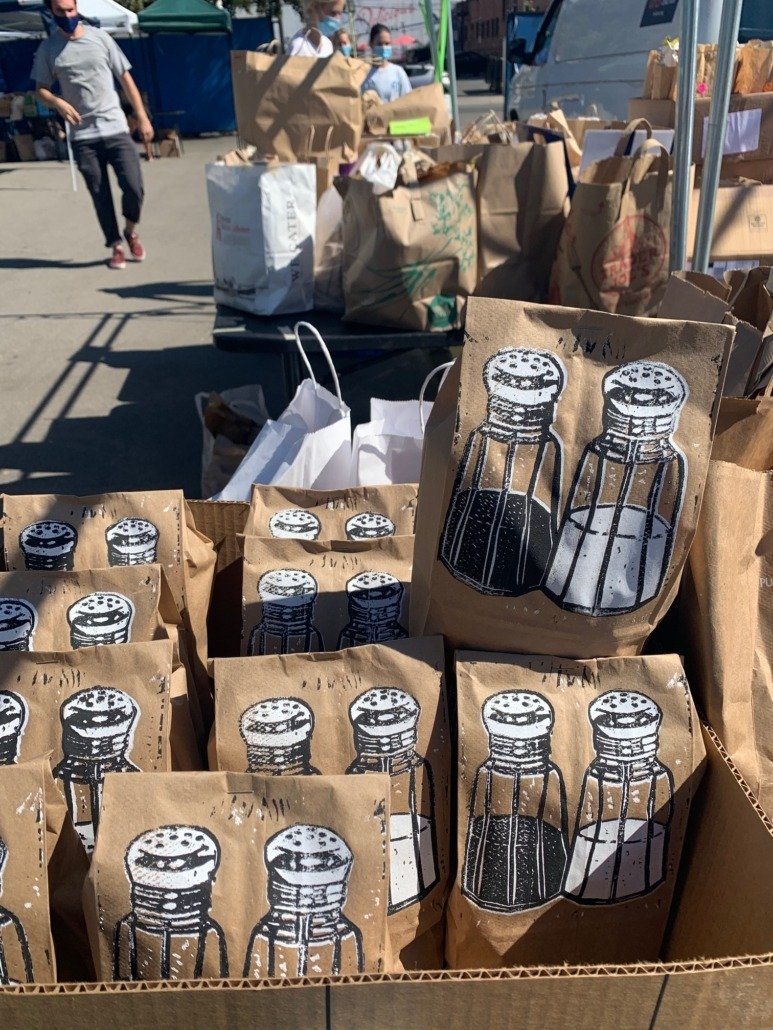 Bags with black and white salt and pepper shaker illustrations at an outdoor market.