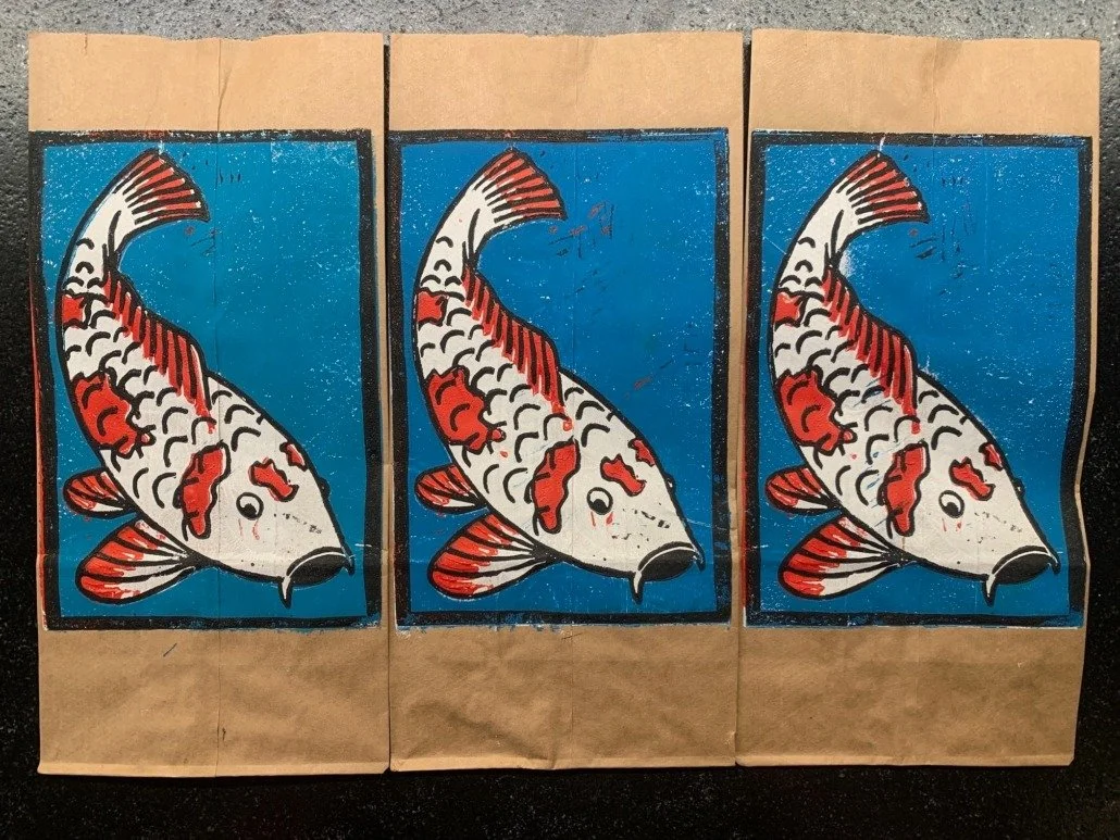 Three paper bags each featuring a colorful koi fish illustration against a blue background.