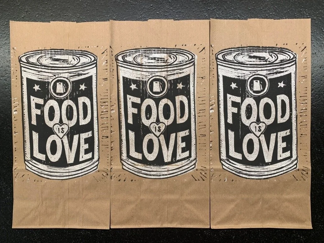 Three brown paper bags with black and white artwork depicting a can with the words "Food is Love" and a heart with the words "is" inside.