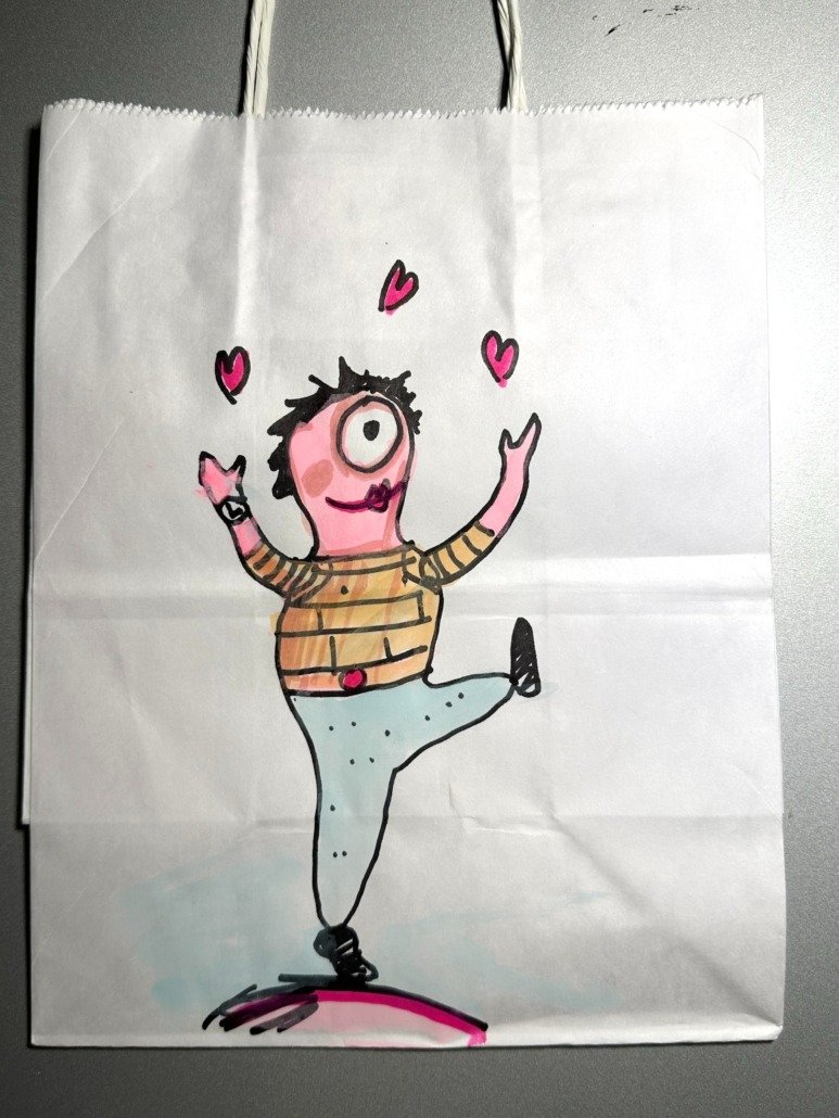 A hand-drawn cartoon character with one large eye, black messy hair, pink cheeks, and a big smile, standing on one leg with arms raised, surrounded by pink hearts, wearing a striped shirt, light blue pants with black dots, and black shoes, on a pink 