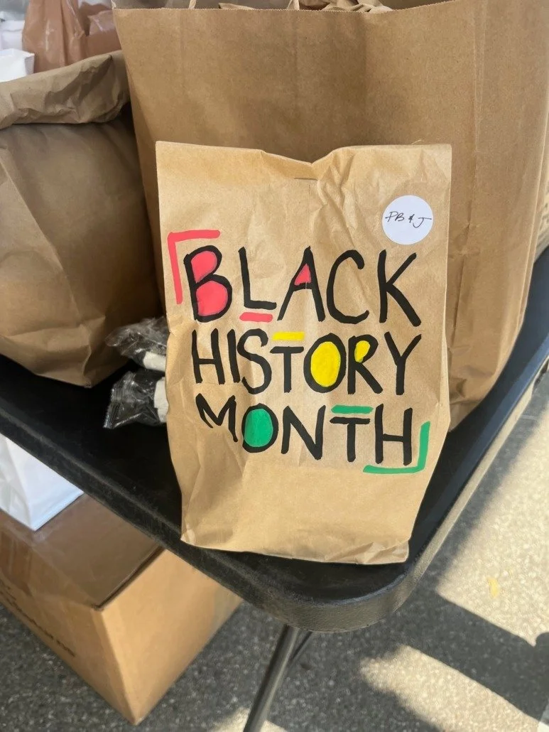 A paper bag with colorful handwritten text that reads 'Black History Month' and various colored markings.