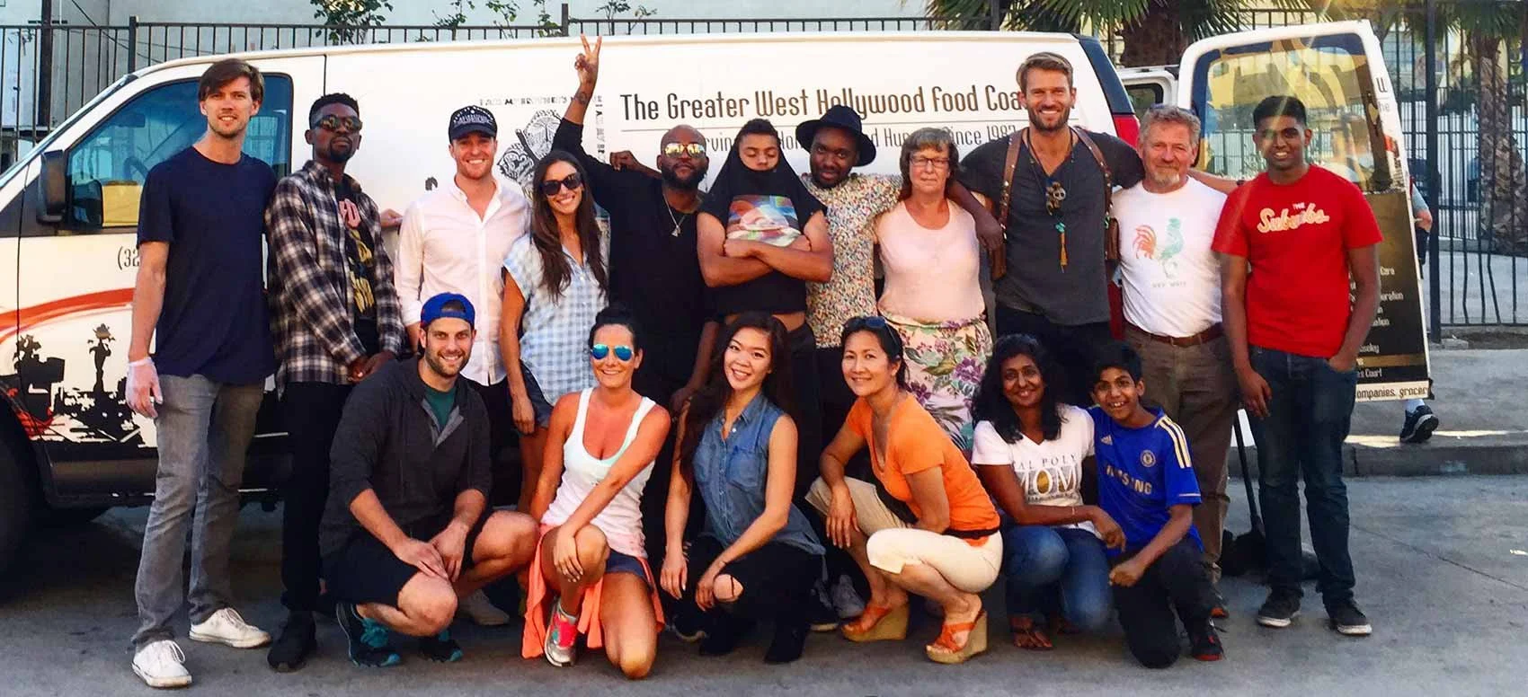 Group of diverse people smiling and posing in front of a food truck that reads 'The Greater West Hollywood Food Coalition'.