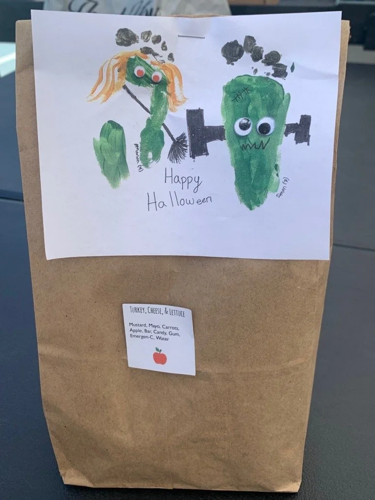 Handmade Halloween card with a drawing of a witch and a Frankenstein monster, both made from vegetables, with googly eyes. The witch is holding a broom and has orange hair, while the Frankenstein has bolts on its head and black stitches. The words "H