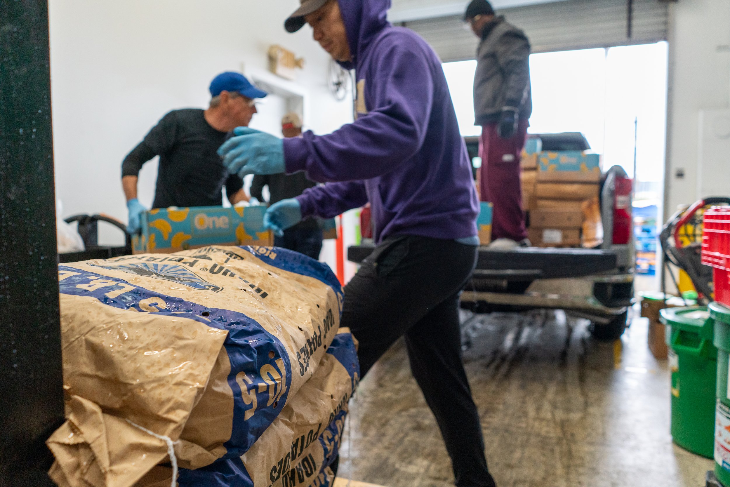 People loading donation items into a truck on an indoor loading dock.