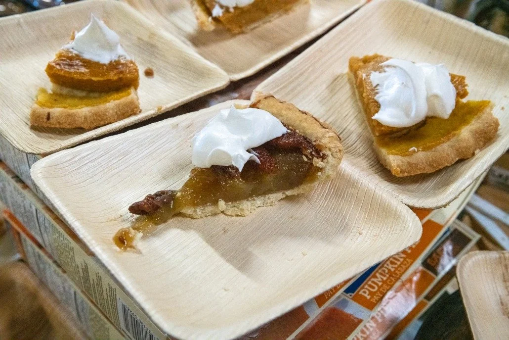 Slices of pumpkin pie with whipped cream on small paper plates.