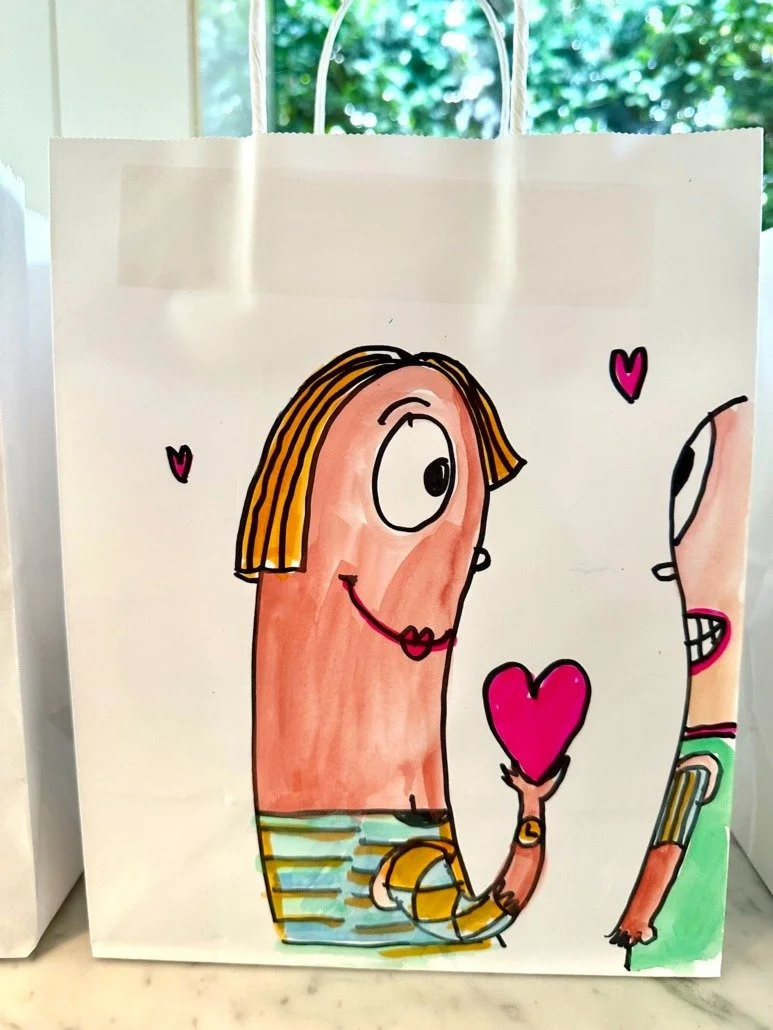 A cartoon illustration of a woman with a large nose, blonde hair, and striped yellow and blue shirt, holding a pink heart, with a partial face of another person also holding a pink heart, on a white bag.