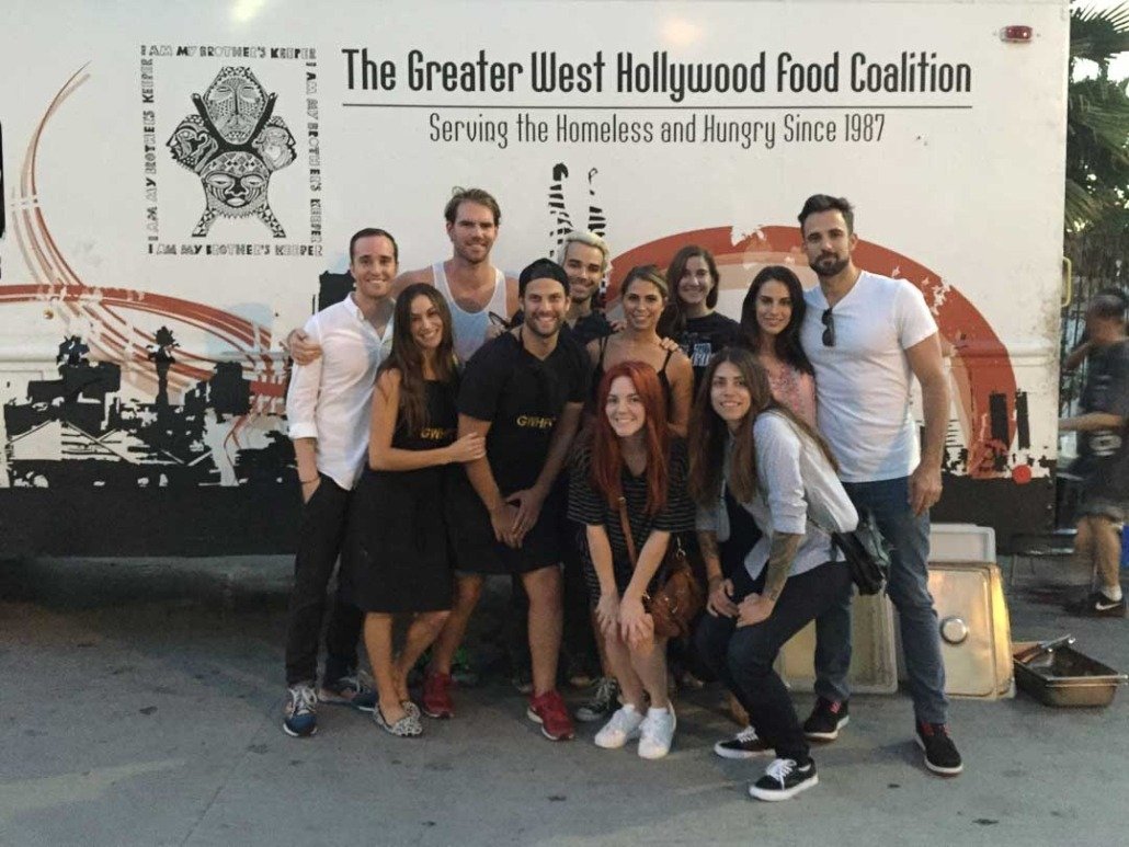 Group of ten people posing in front of a large white bus with 