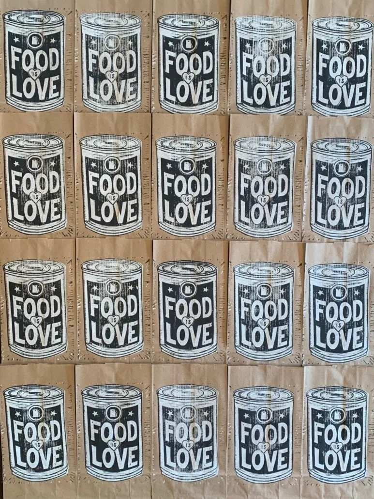 Pattern of cans with the phrase "Food is Love" written on them, arranged in a grid pattern on a surface.