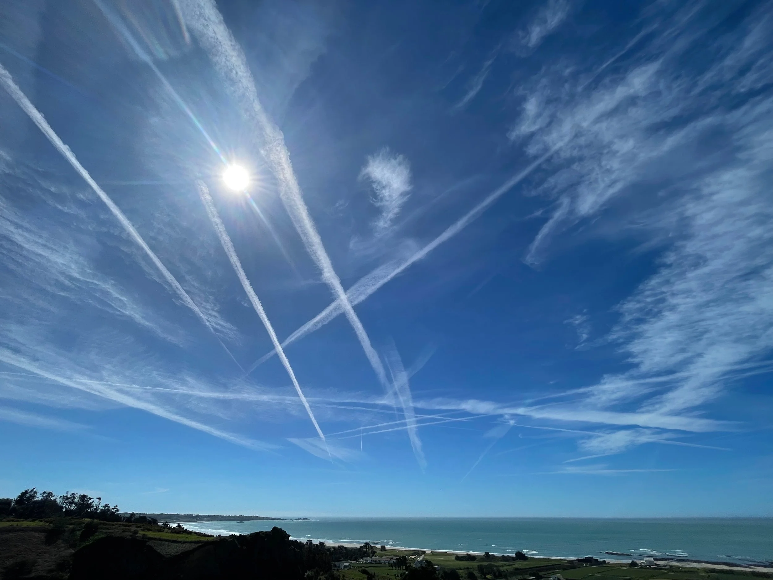 The view from the headland and ceremony area at La Robeline Jersey, Channel Islands.  In dues crossing each other. The landscape below shows a coastal scene with a shoreline. In the distance you can see Rocco Tower and iconic Corbiere Lighthouse