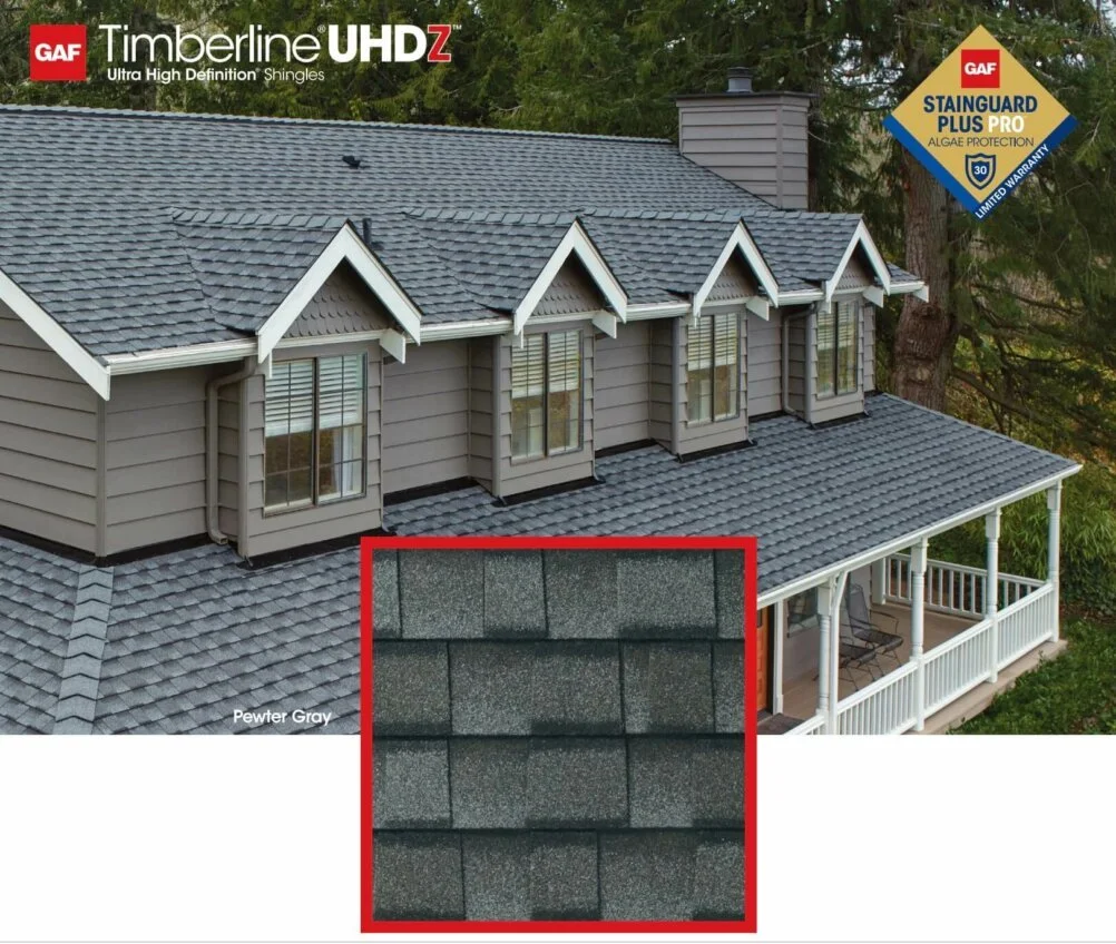 Photo of a house roof with gray GAF Timberline UHDZ shingles, showing multiple dormer windows and a balcony, with a close-up inset of the shingles' texture in pewter gray.