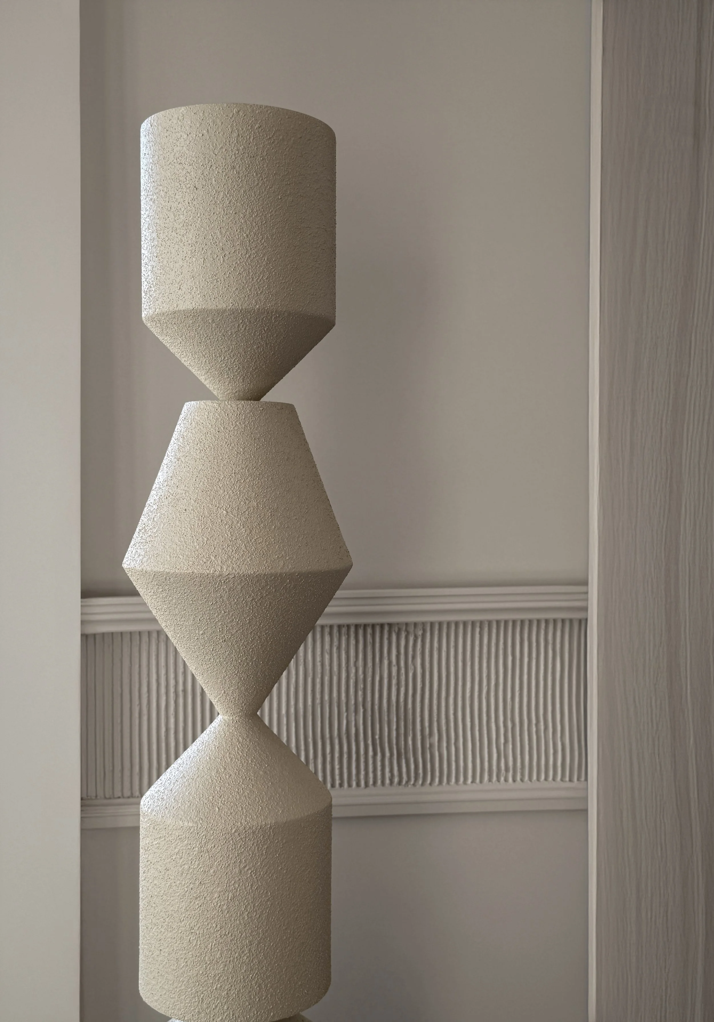 Interior design detail in Kensington Penthouse by Jenny Ly Studio — sculptural textured column set against refined wall moulding