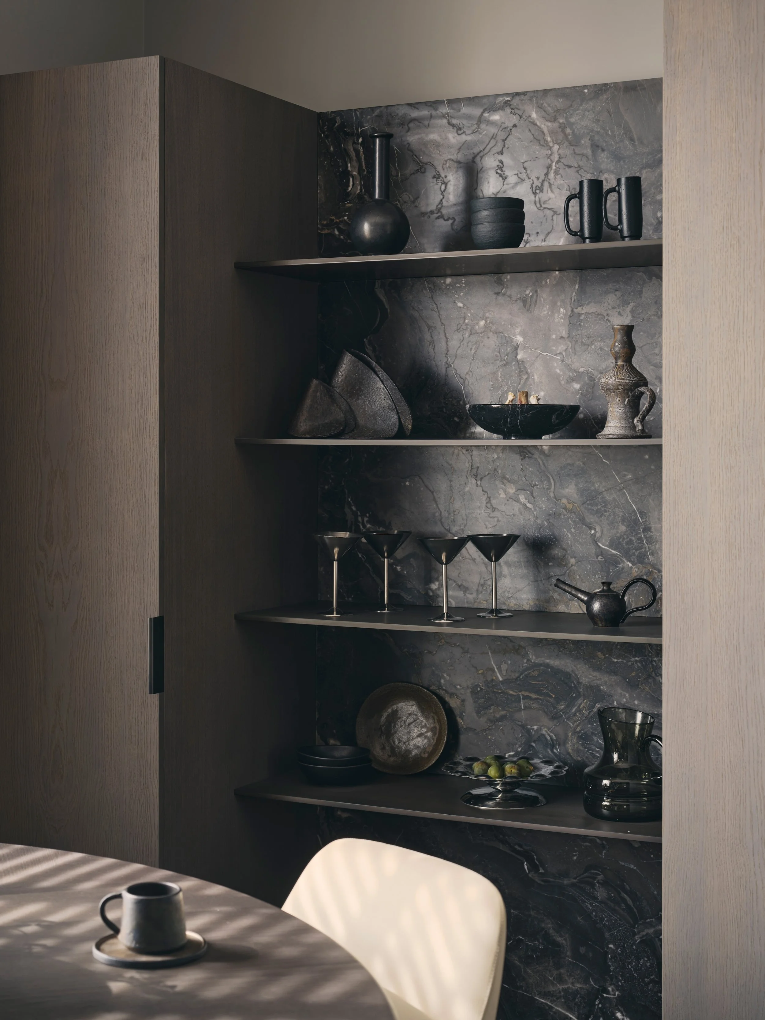 Interior design detail by Jenny Ly Studio — dark stone shelving with ceramics in Holland Park Residence, London.