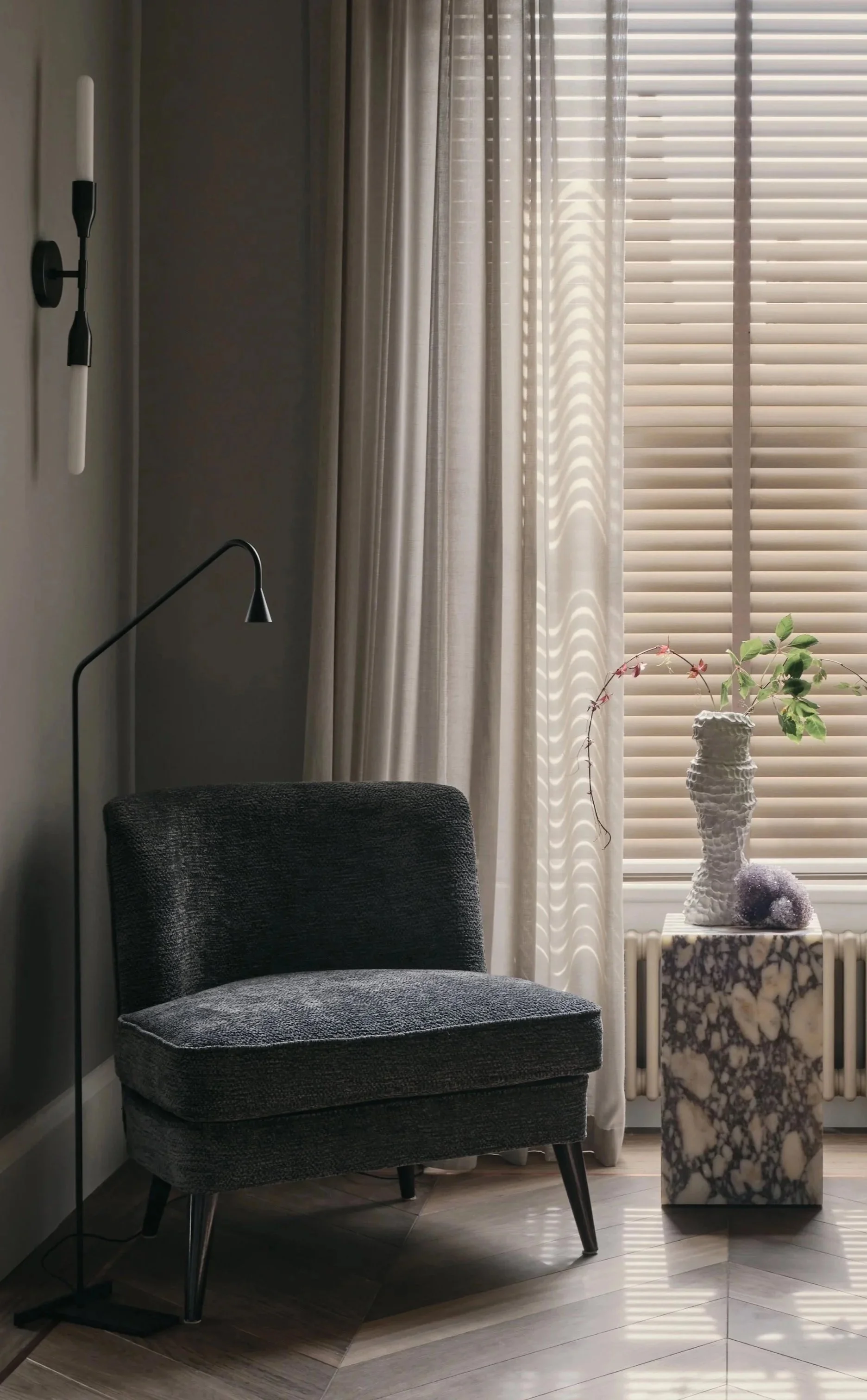 Reading corner interior design in Holland Park Residence by Jenny Ly Studio, featuring a dark armchair, marble pedestal, and soft daylight.