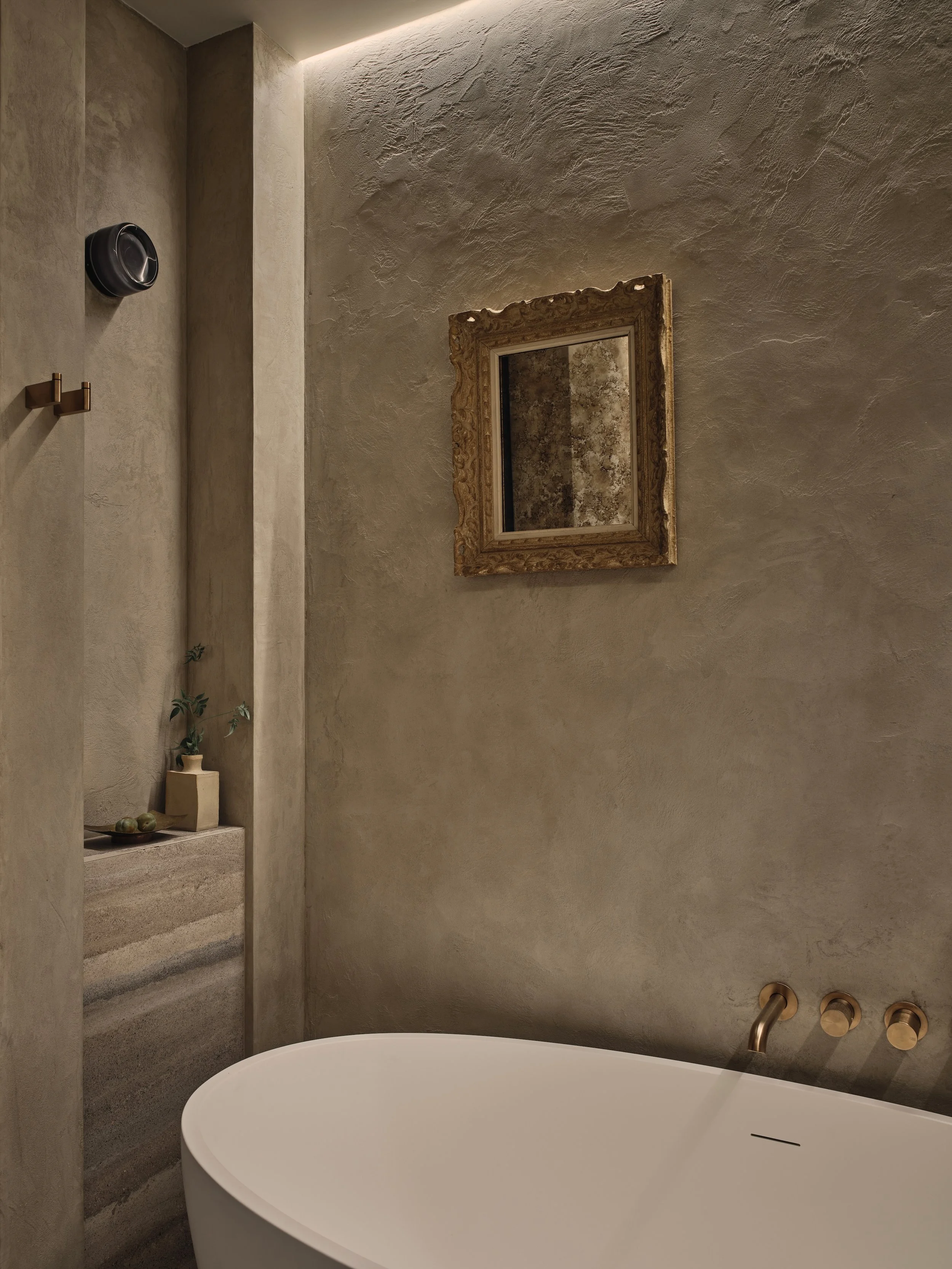 Bathroom interior design in Holland Park Residence by Jenny Ly Studio — soft plastered walls, aged brass fittings, and sculptural freestanding bathtub.