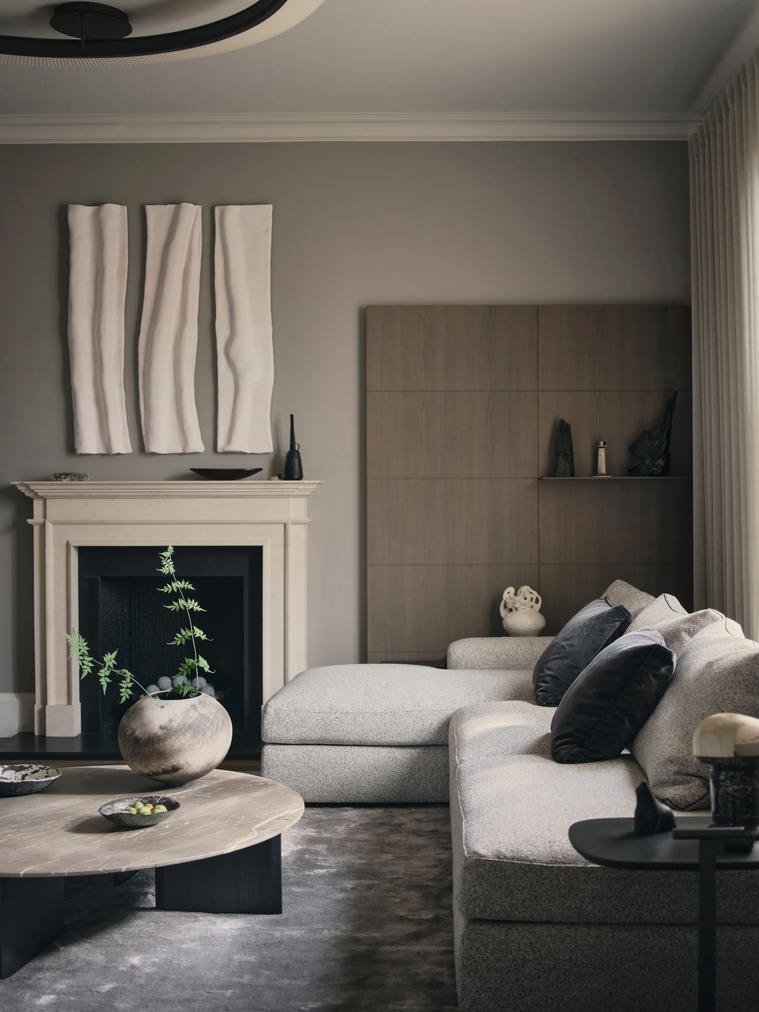 Living room interior design by Jenny Ly Studio in Holland Park Residence — calm composition of stone fireplace, neutral textiles, and sculptural decor.