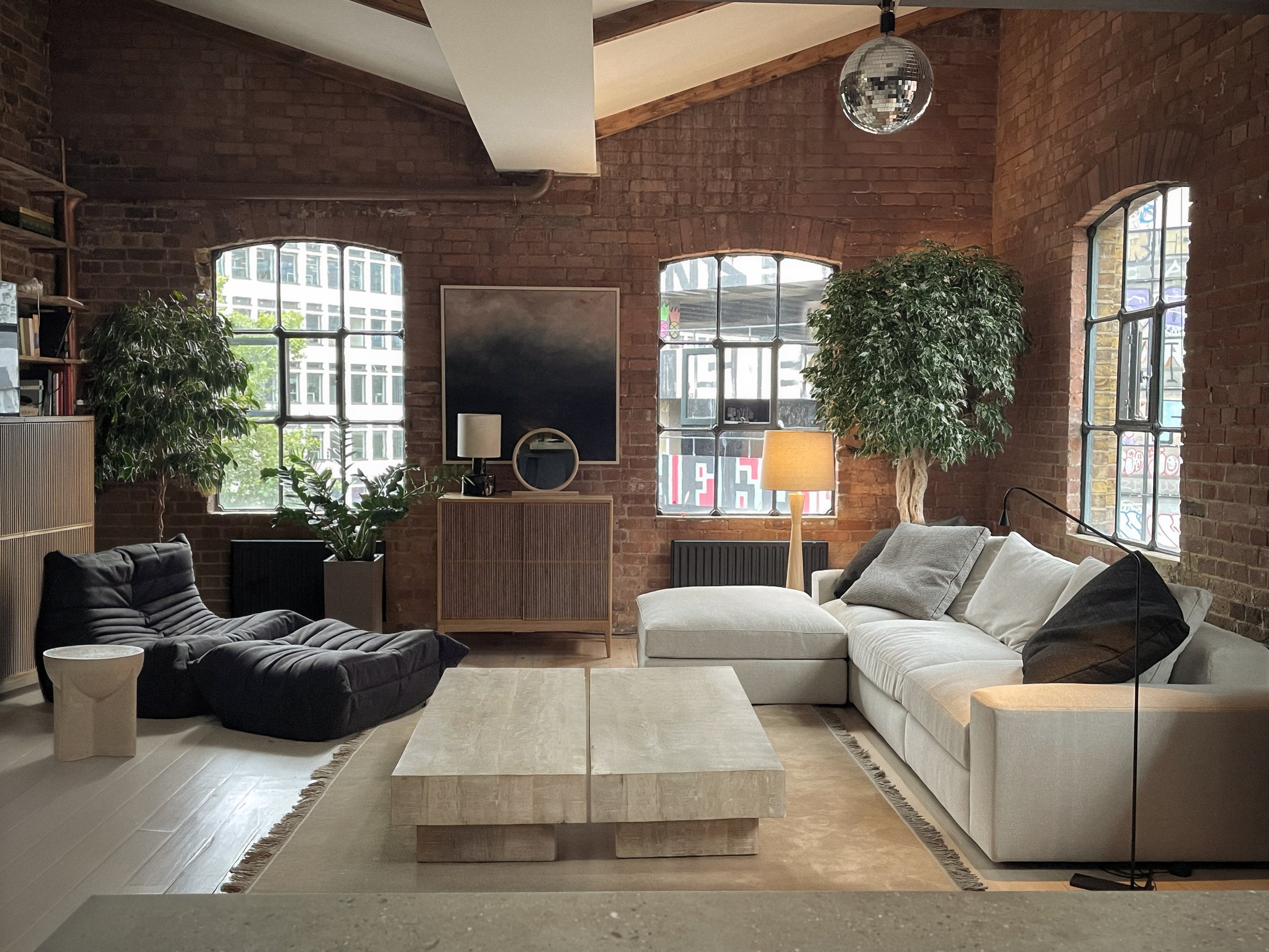 Loft living room furnished by Jenny Ly Studio — layered light, wooden coffee table, natural textures and calm presence.