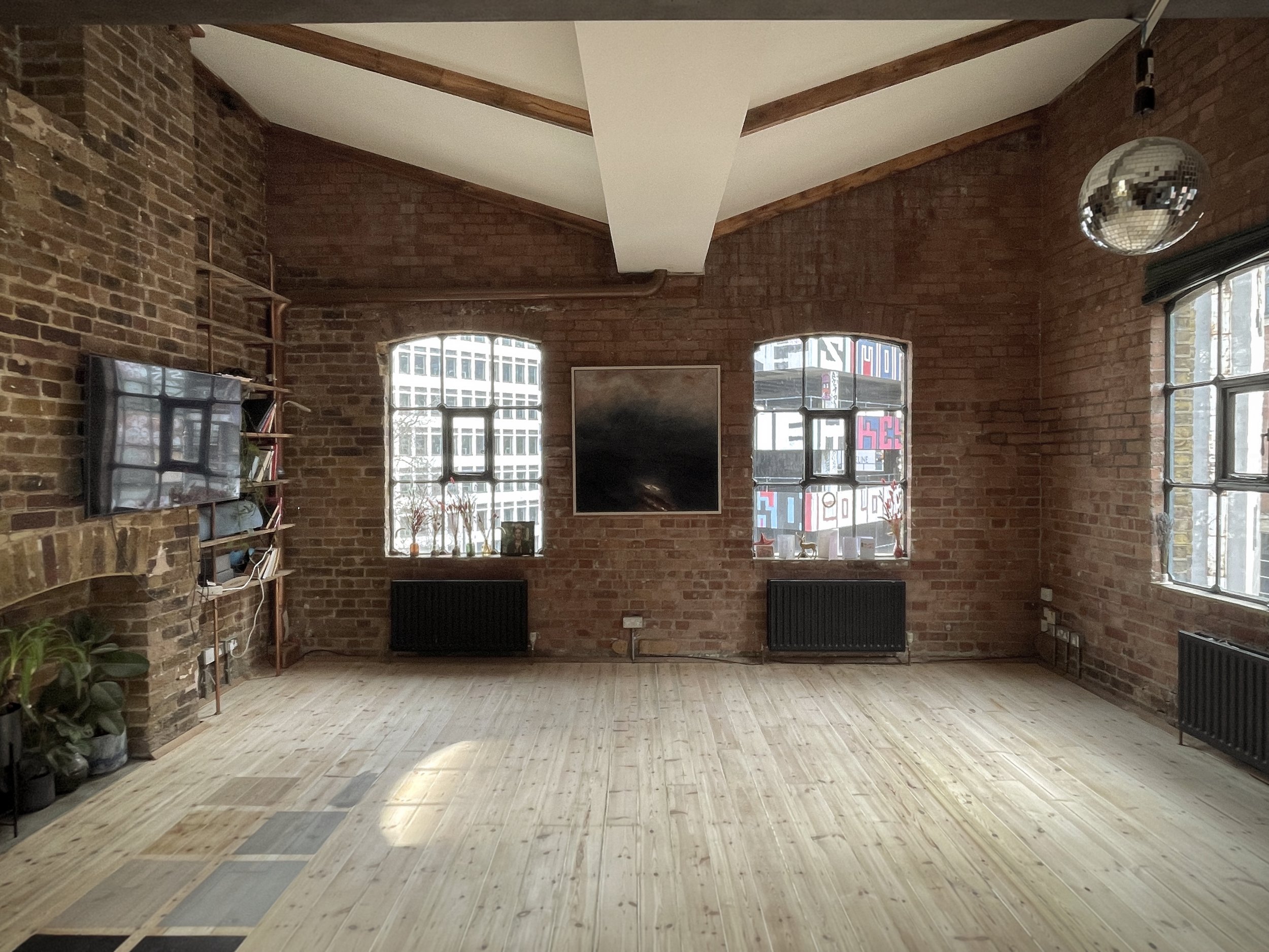 Loft interior before furnishing — exposed brick walls, natural light and open space awaiting atmosphere and texture.