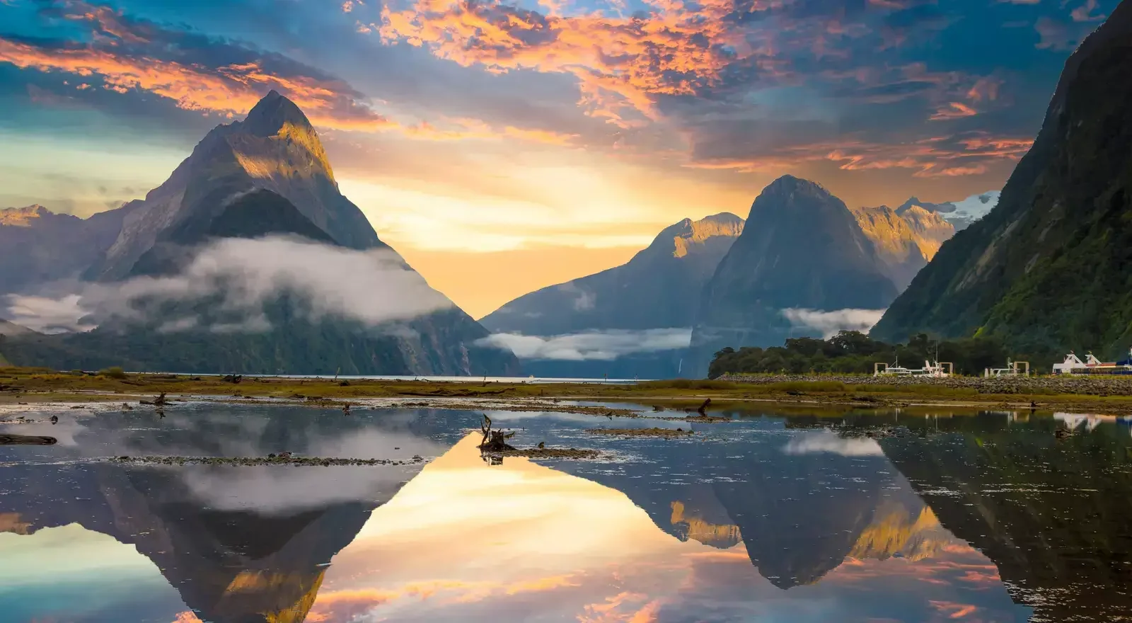 Scenic view of mountains at sunrise or sunset with a calm body of water reflecting the mountains and sky.
