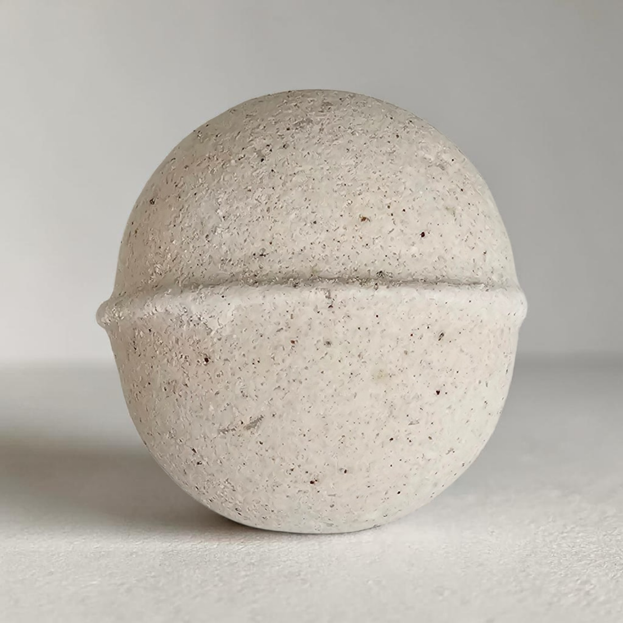 Close-up of a speckled white eggshell, showing its texture and curved shape against a plain background.