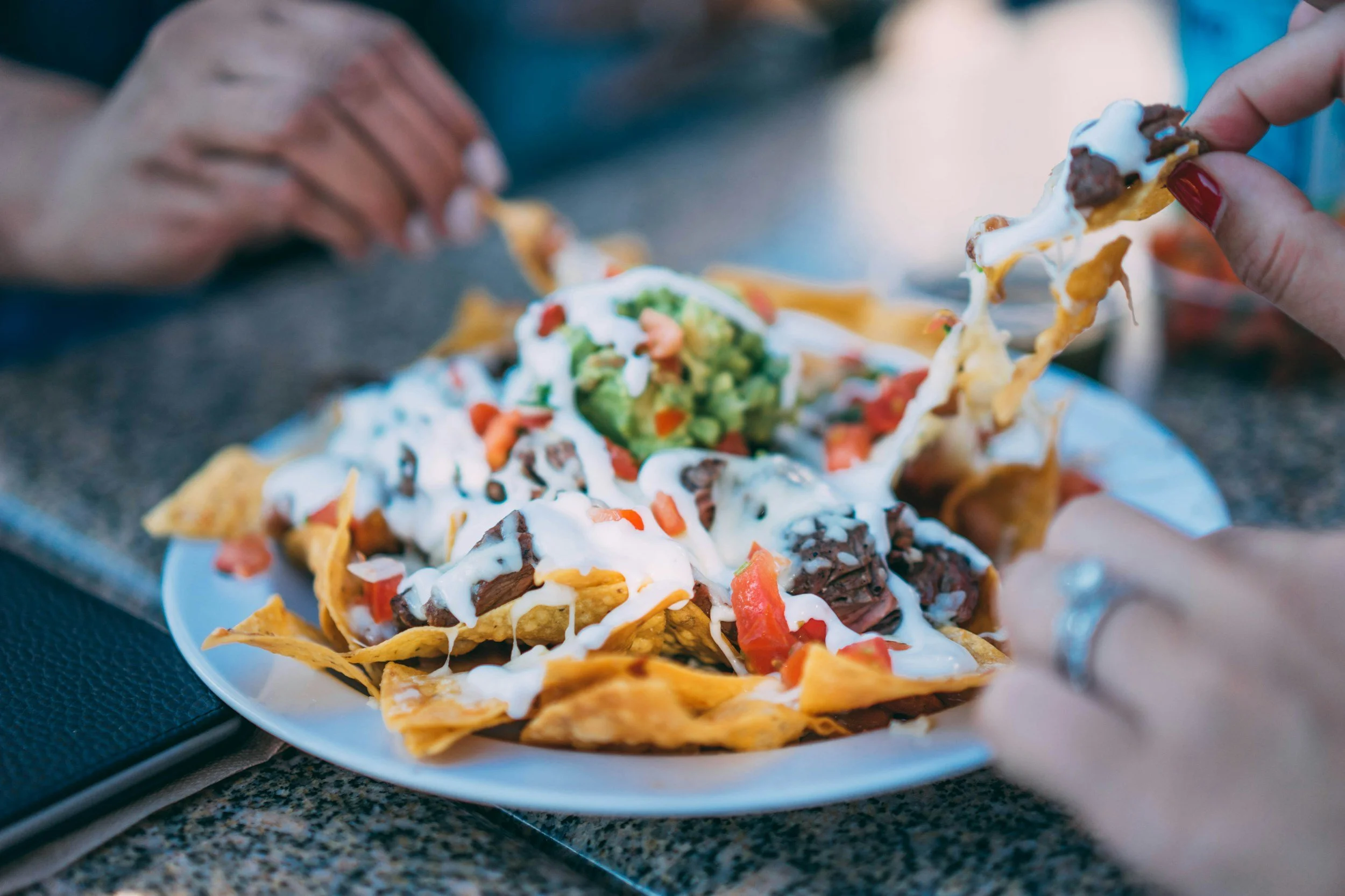 friends sharing nachos, chips with cheese, beef, avocado, salsa