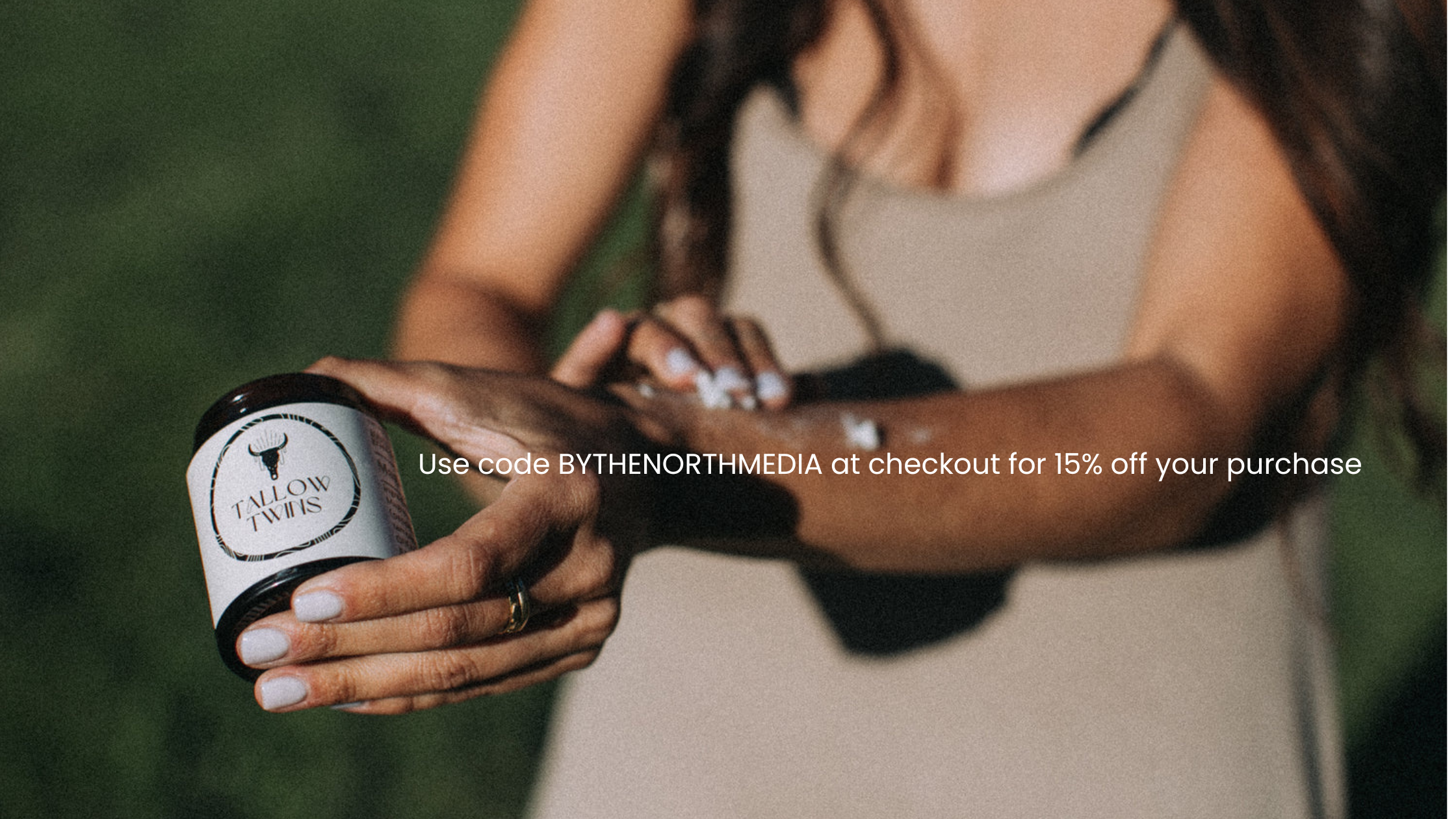 A woman holding a container labeled 'Tallow Twins' in an outdoor setting. The woman appears to be applying or showing the product, with text overlay promoting a discount code for 15% off.