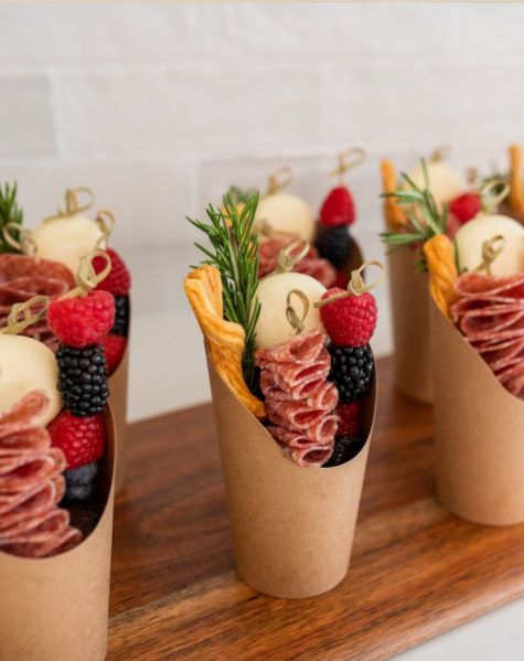 Individual charcuterie cups with cured meat, cheese, berries, and herbs