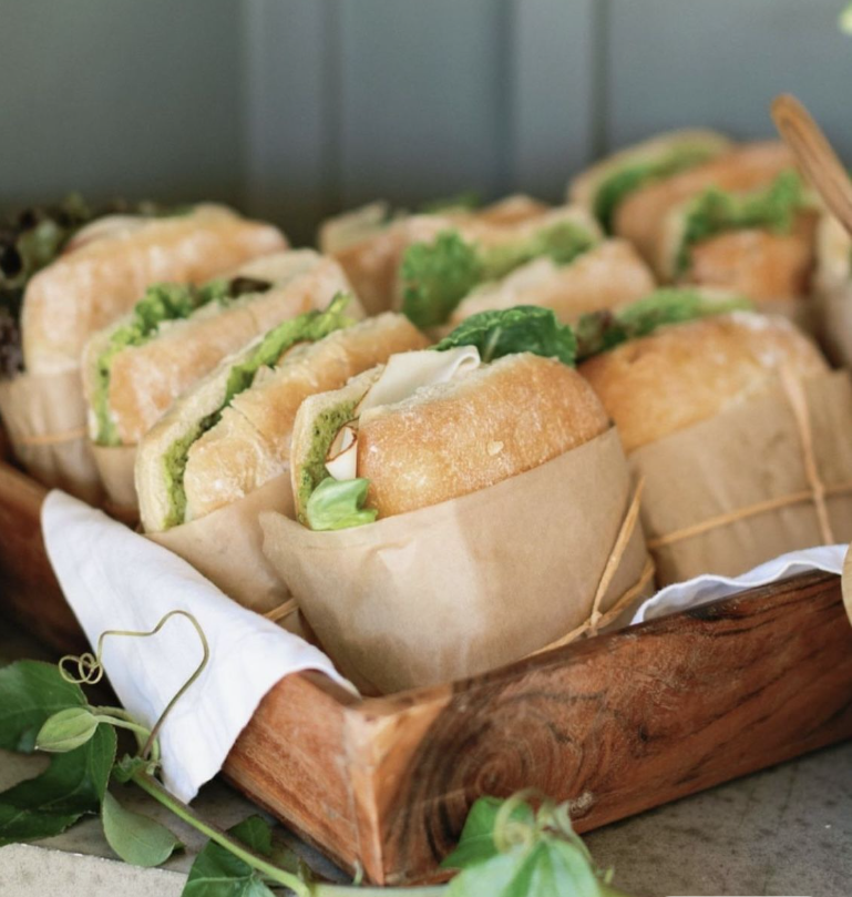 A tray of sandwiches wrapped in brown paper, with lettuce and bread visible.
