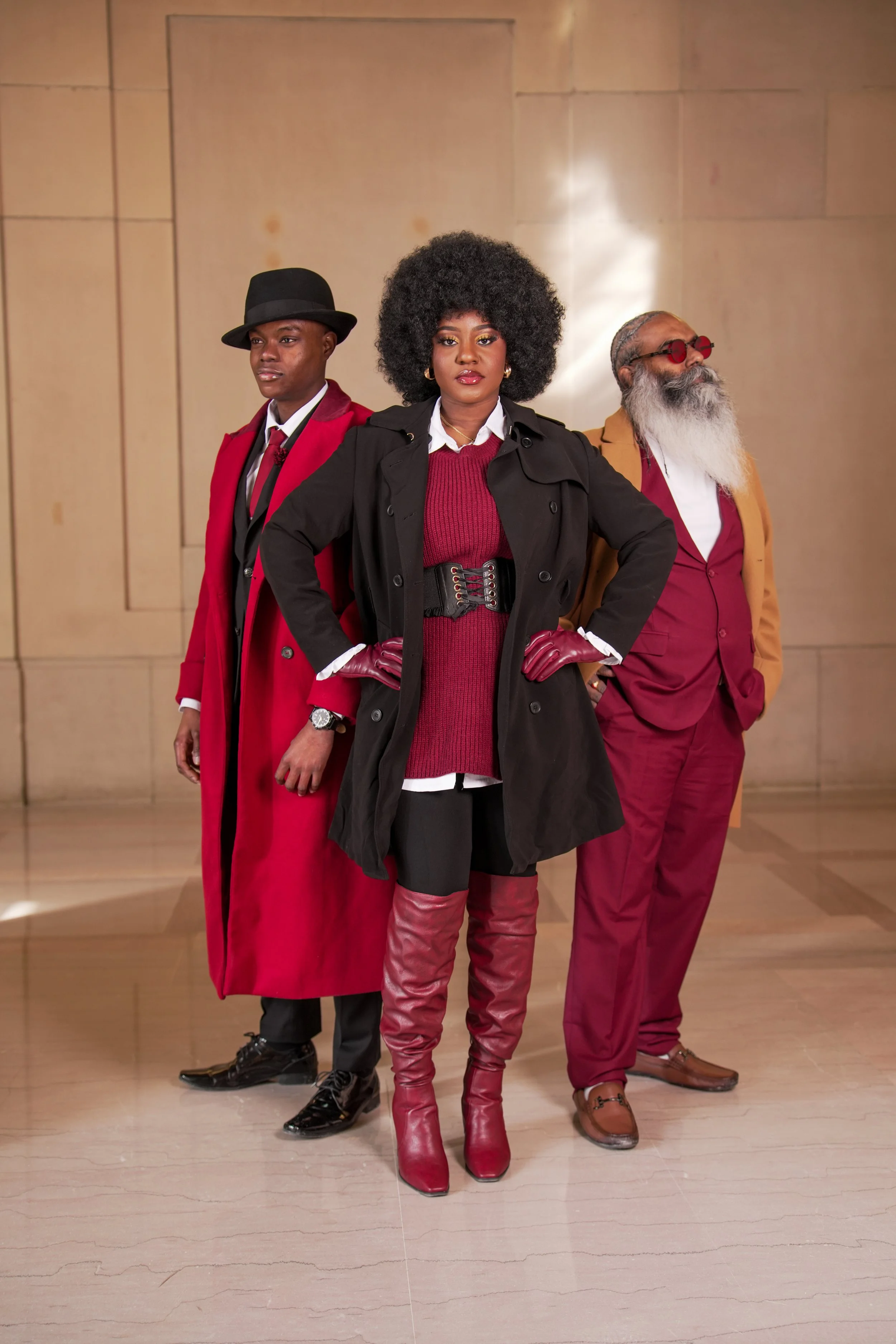 Three stylish individuals dressed in red and black clothing, standing confidently indoors against a beige wall. Black History Month Social Media campaign photoshoot inspiration. Social media.