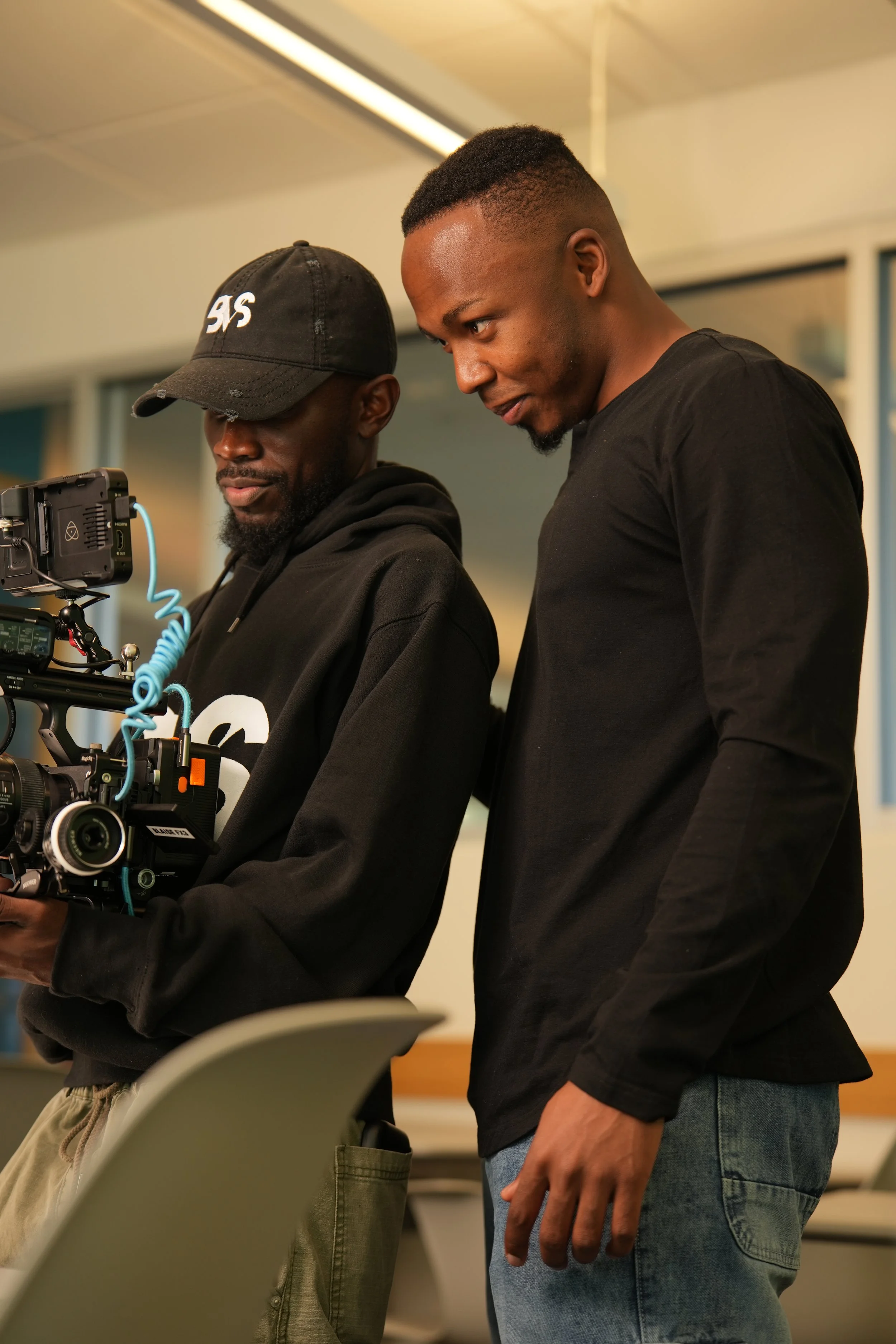 Two young men looking at a professional camera equipment on a film set.