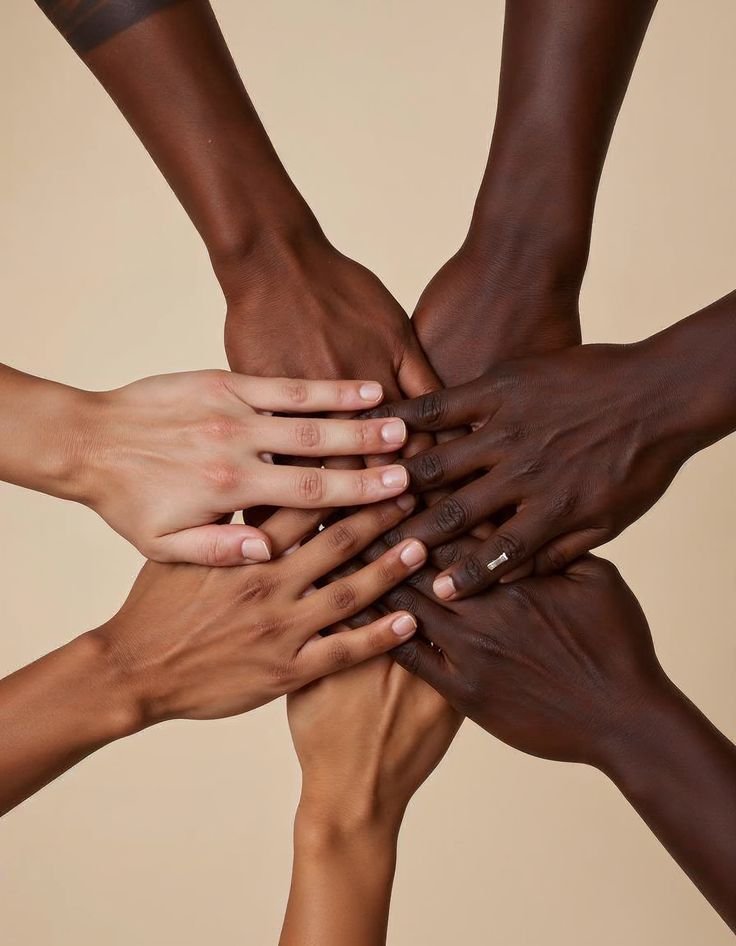 Multiple hands of different skin tones stacked together in a symbol of unity.