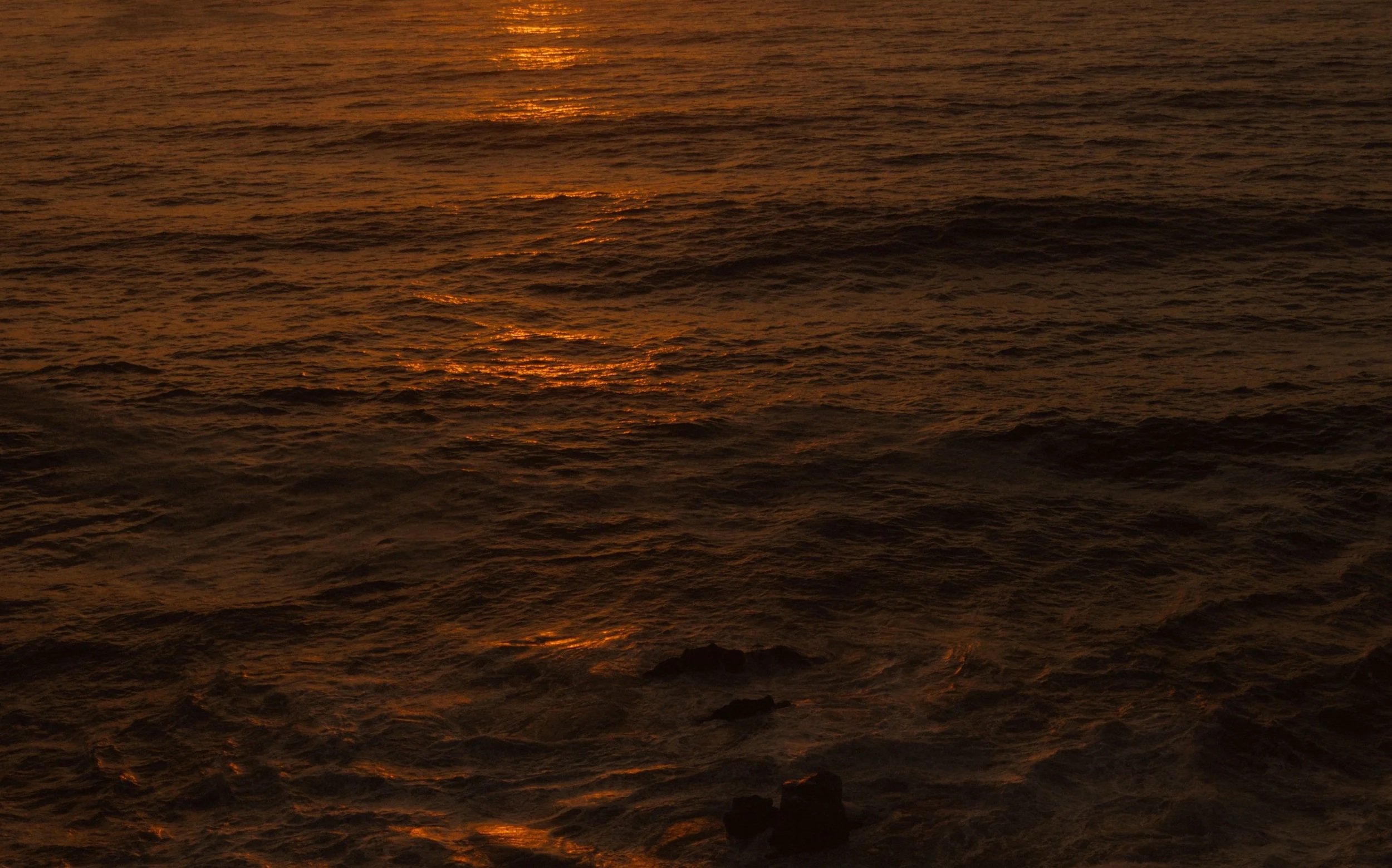 Sunset over the ocean with orange reflections on the water
