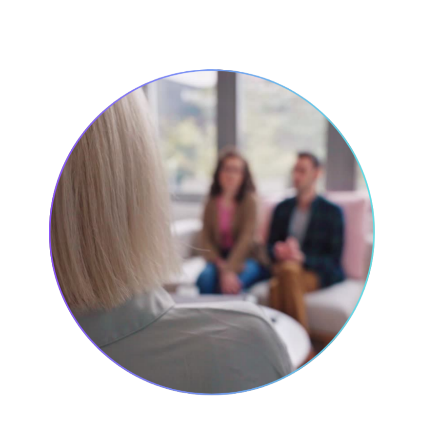 A counseling session with a therapist talking to a man and woman in a therapy office.