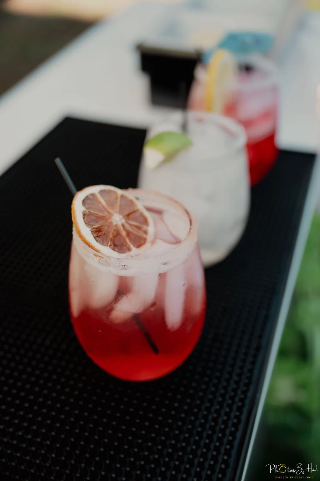 a row of three cocktails lined up on the bar top