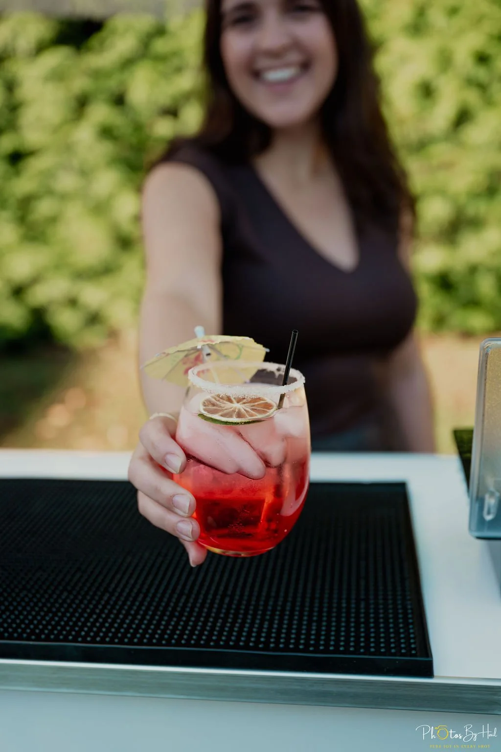 The owner, Cara, holding out a cocktail drink towards the camera