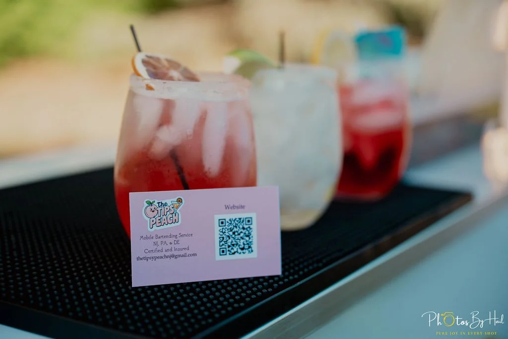 The Tipsy Peach business card displayed leaning up against a cocktail