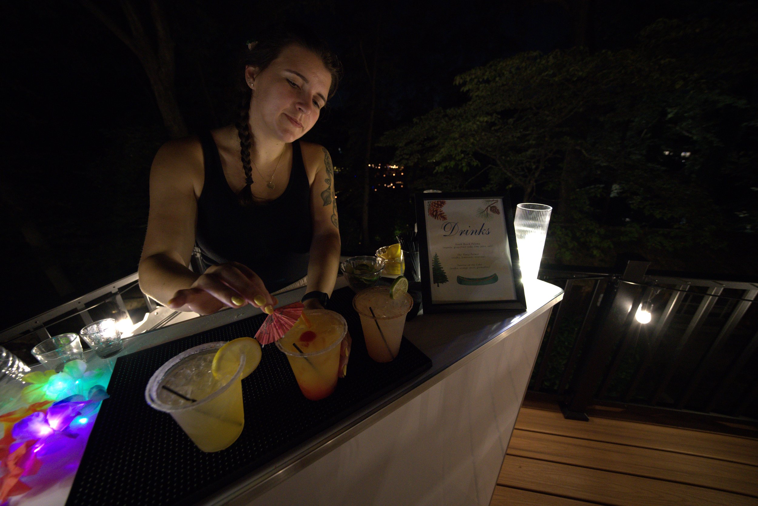 the owner, Cara, behind the bar placing a garnish into a cocktail drink