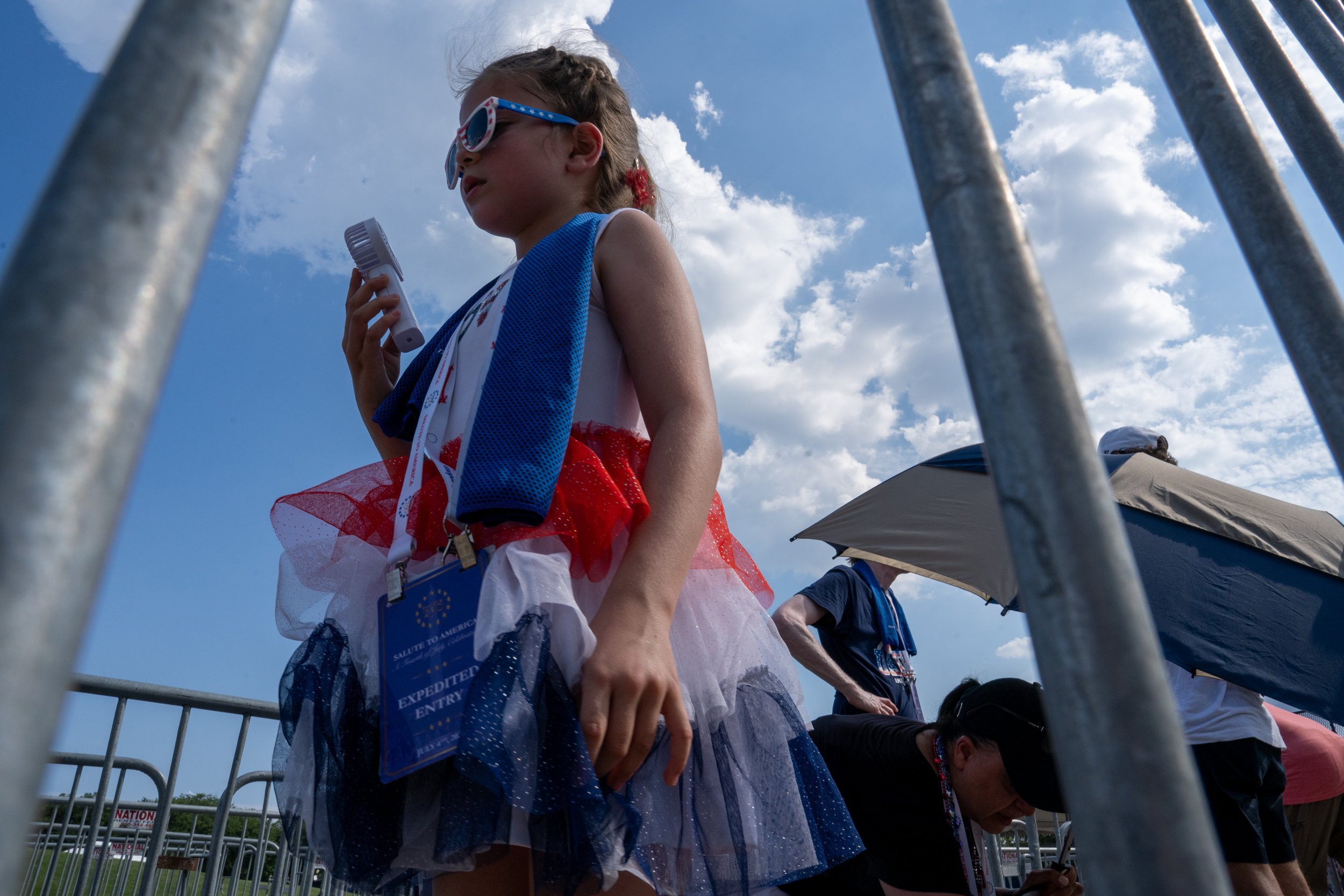 A child holds a portable fan while waiting to gain entry to the Fourth of July celebration at the National Mall in Washington, D.C., on Saturday, July 4, 2026. (Natasha Kaiser/The Hill)