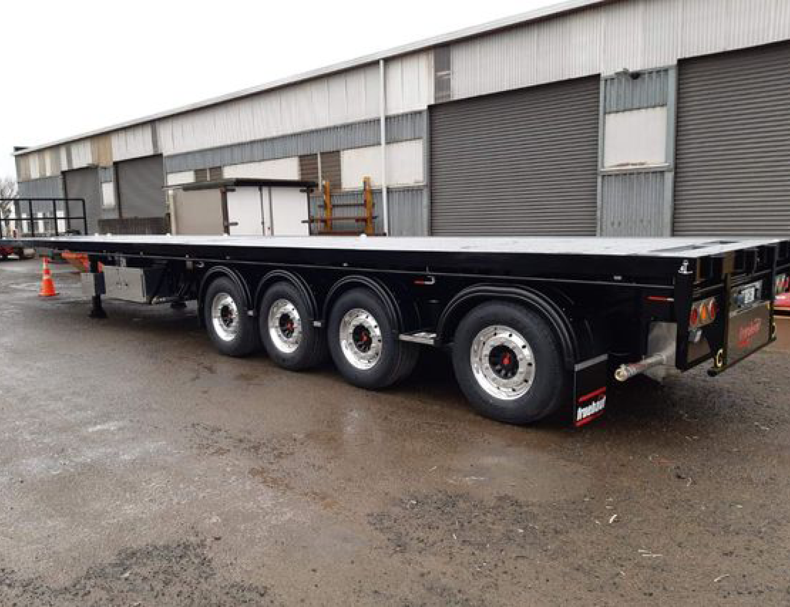 Example image of a flatdeck trailer for Fruehauf NZ, parked in a factory carpark