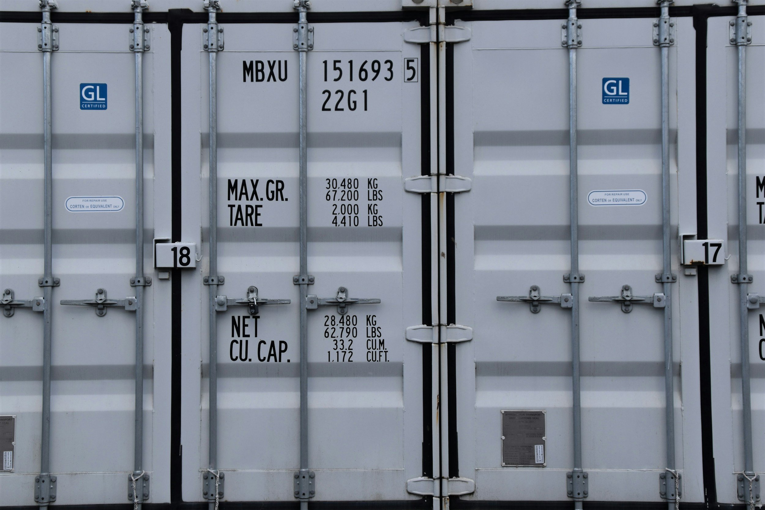 Close-up of the doors of a shipping container with various labels and specifications including weight limits and capacity.