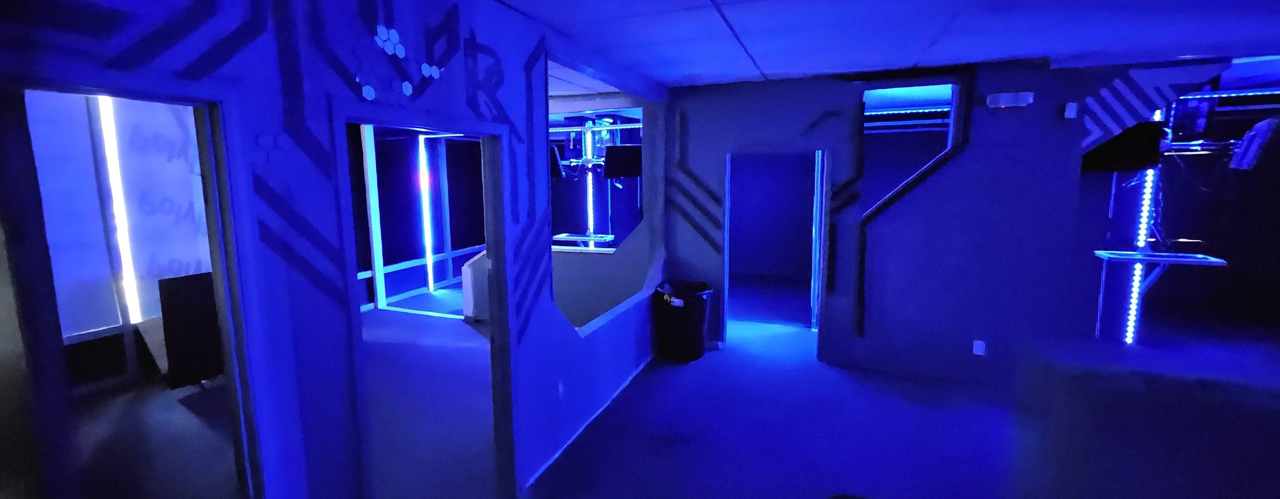 LAZRdojo studio interior — neon-blue arcade panorama