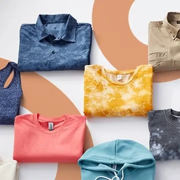 Folded casual shirts in blue, beige, gray, pink, yellow, and teal colors arranged on a patterned surface.