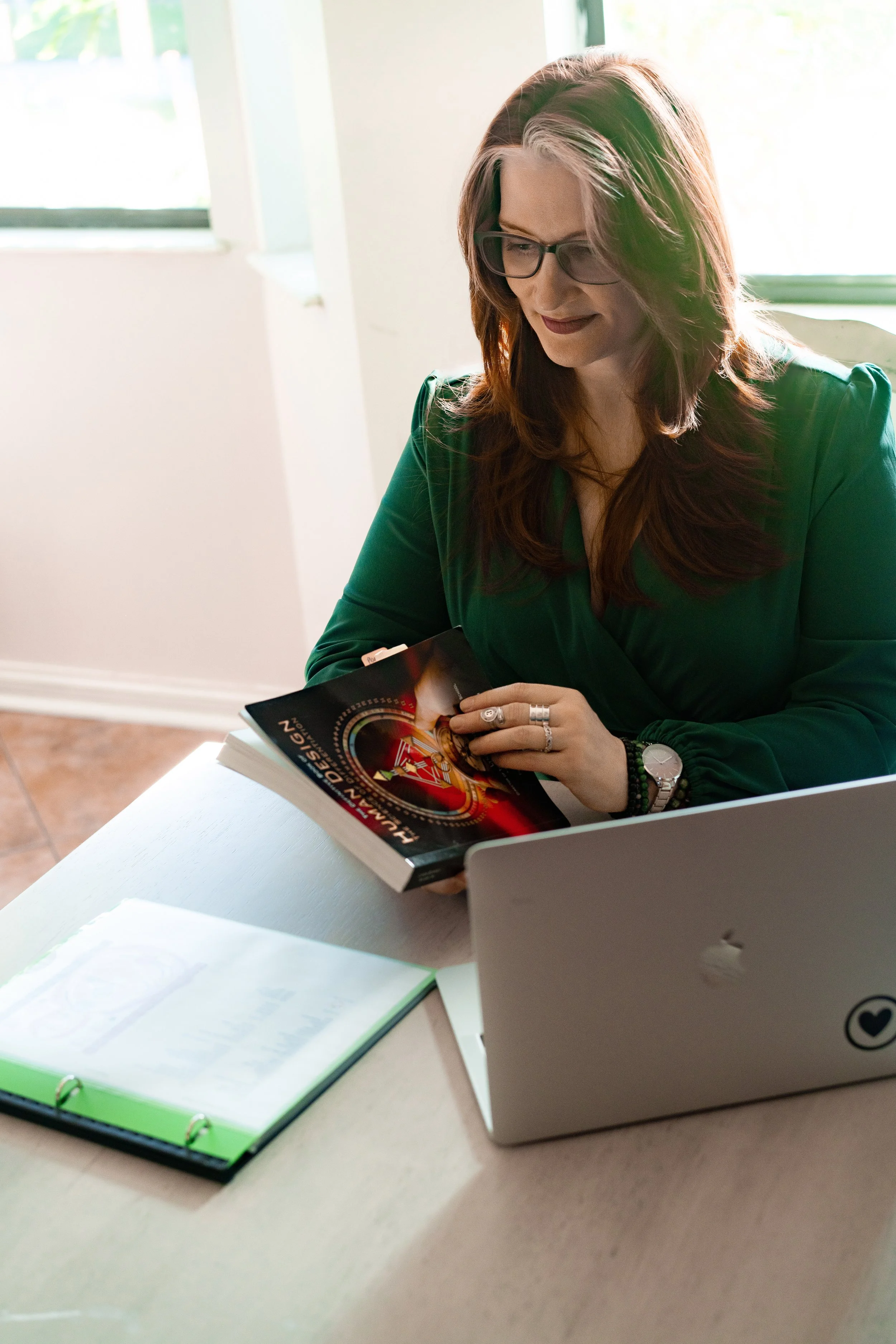 A coach holding a book performing a Human Design Reading & Chart Type.
