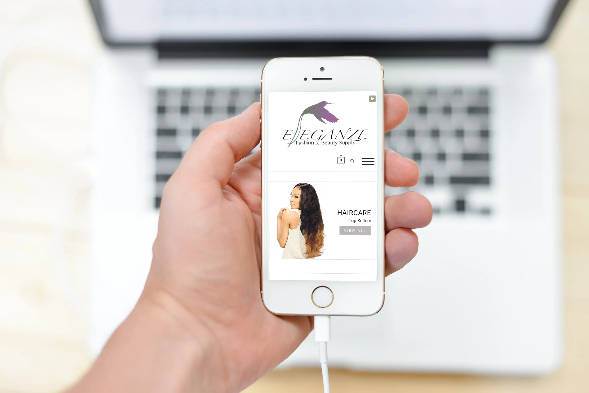 A person holding an iPhone displaying an e-commerce website called "ELEGANCE Fashion & Beauty Supply" with a section for haircare products showing a woman with long dark hair with highlights.
