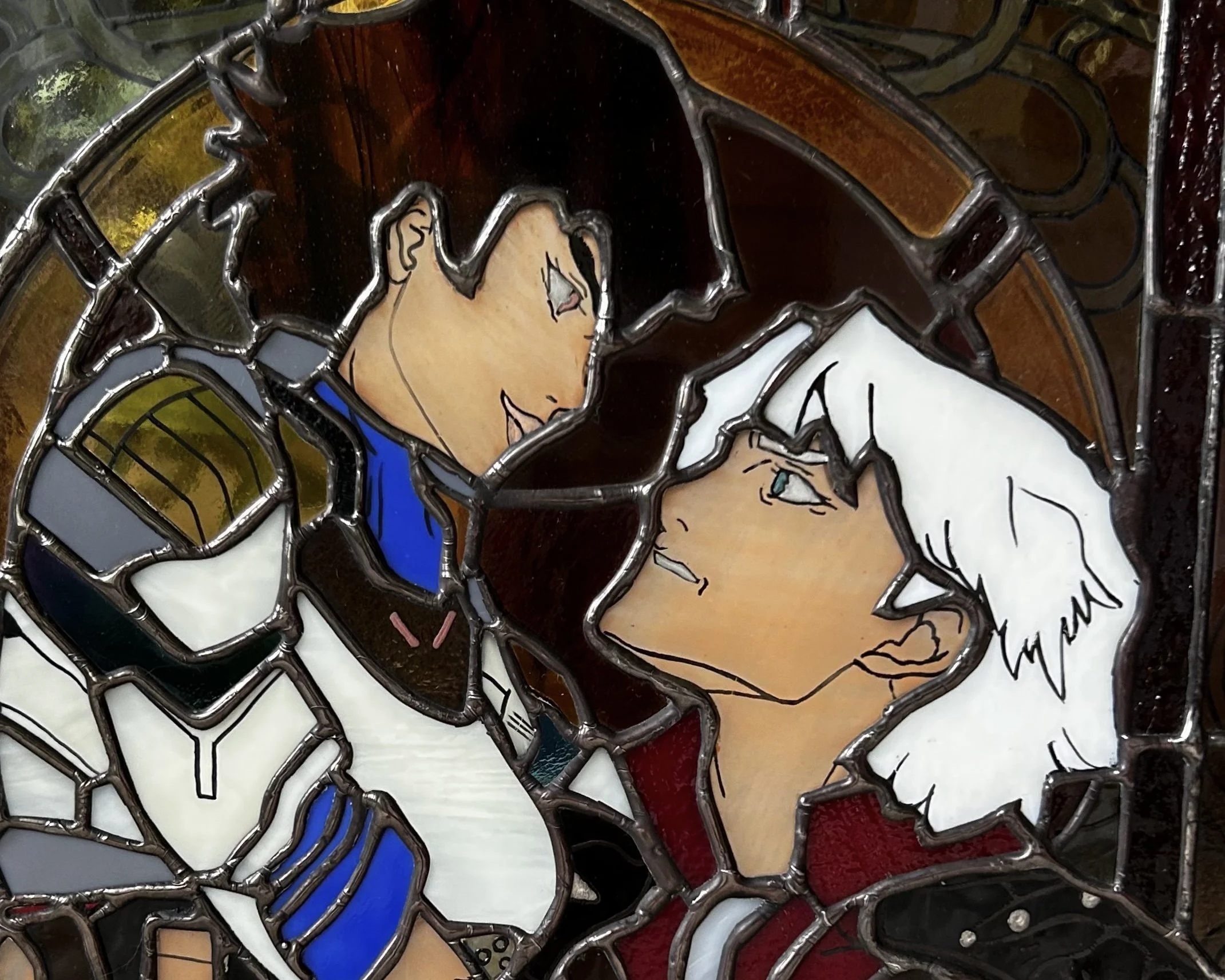 A stained glass artwork depicting two anime-style characters gazing at each other closely, with one having brown hair and the other white hair. Devil May Cry inspired fan art depicting Lady and Dante in a large stained glass panel.