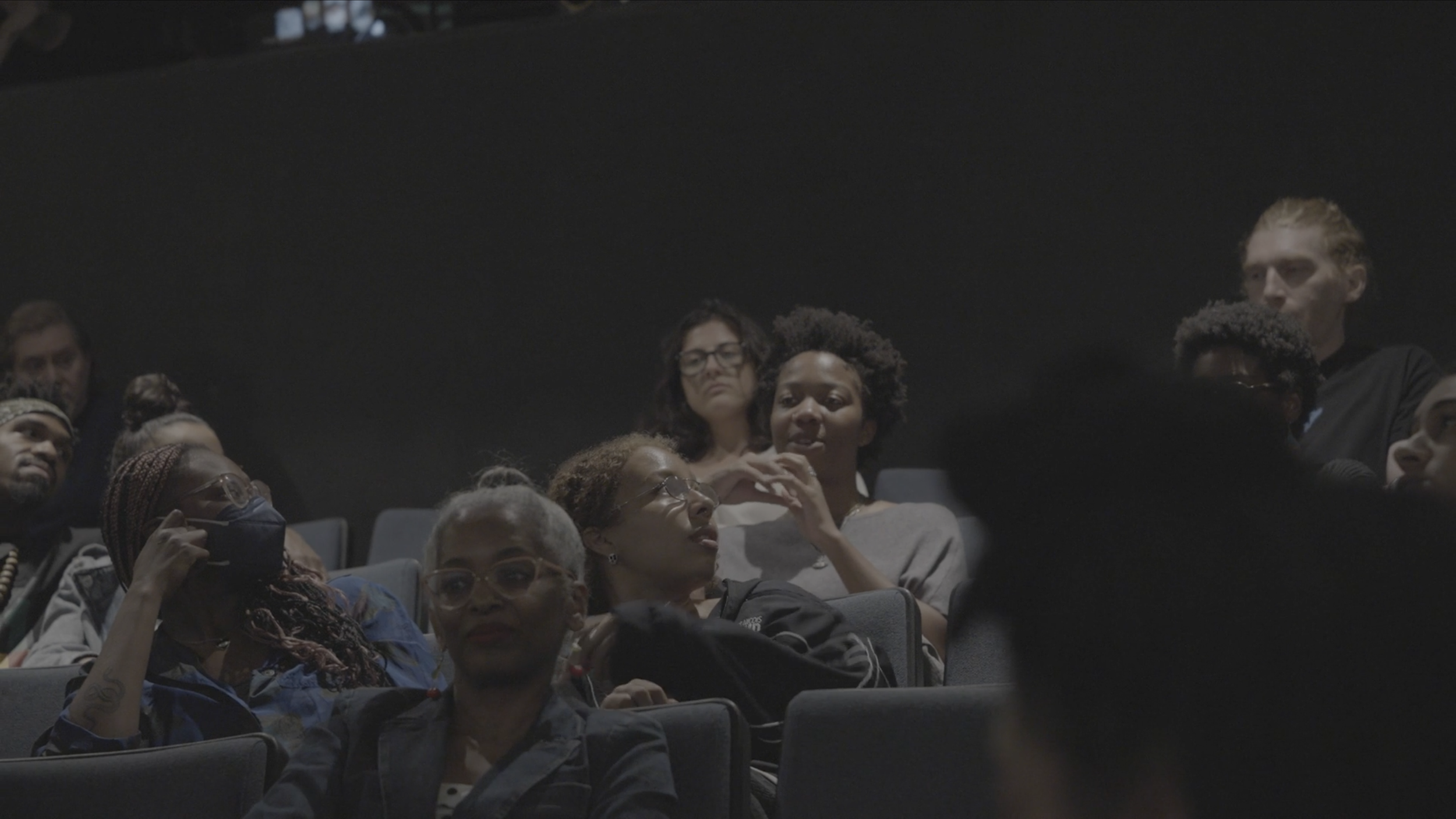 People sitting in an auditorium, some are listening and some are talking
