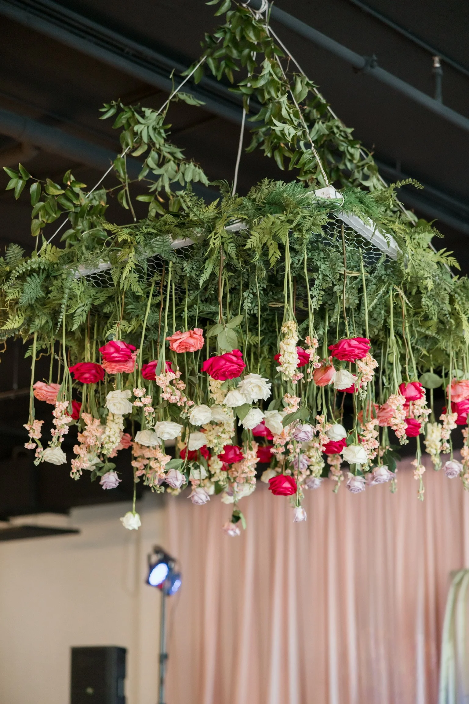 Hanging floral installation at The Velveteen in Madison, MS, with cascading pink, peach, and white roses suspended above the dance floor