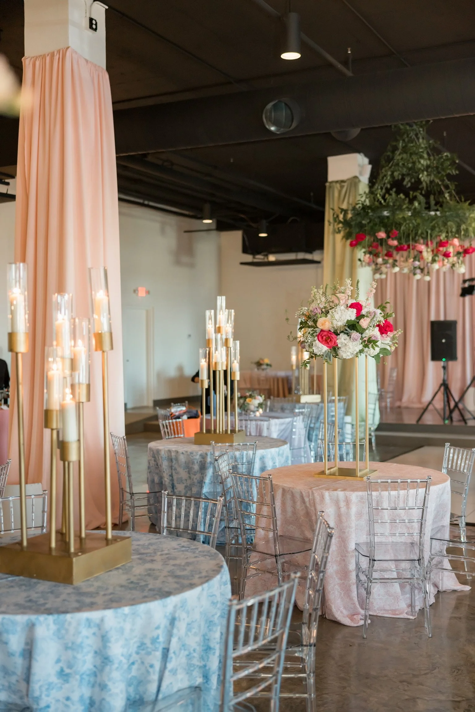 Wedding reception details at The Velveteen wedding venue in Madison, MS, with pastel draped fabric, floral centerpieces, and tall lit candles set across guest tables