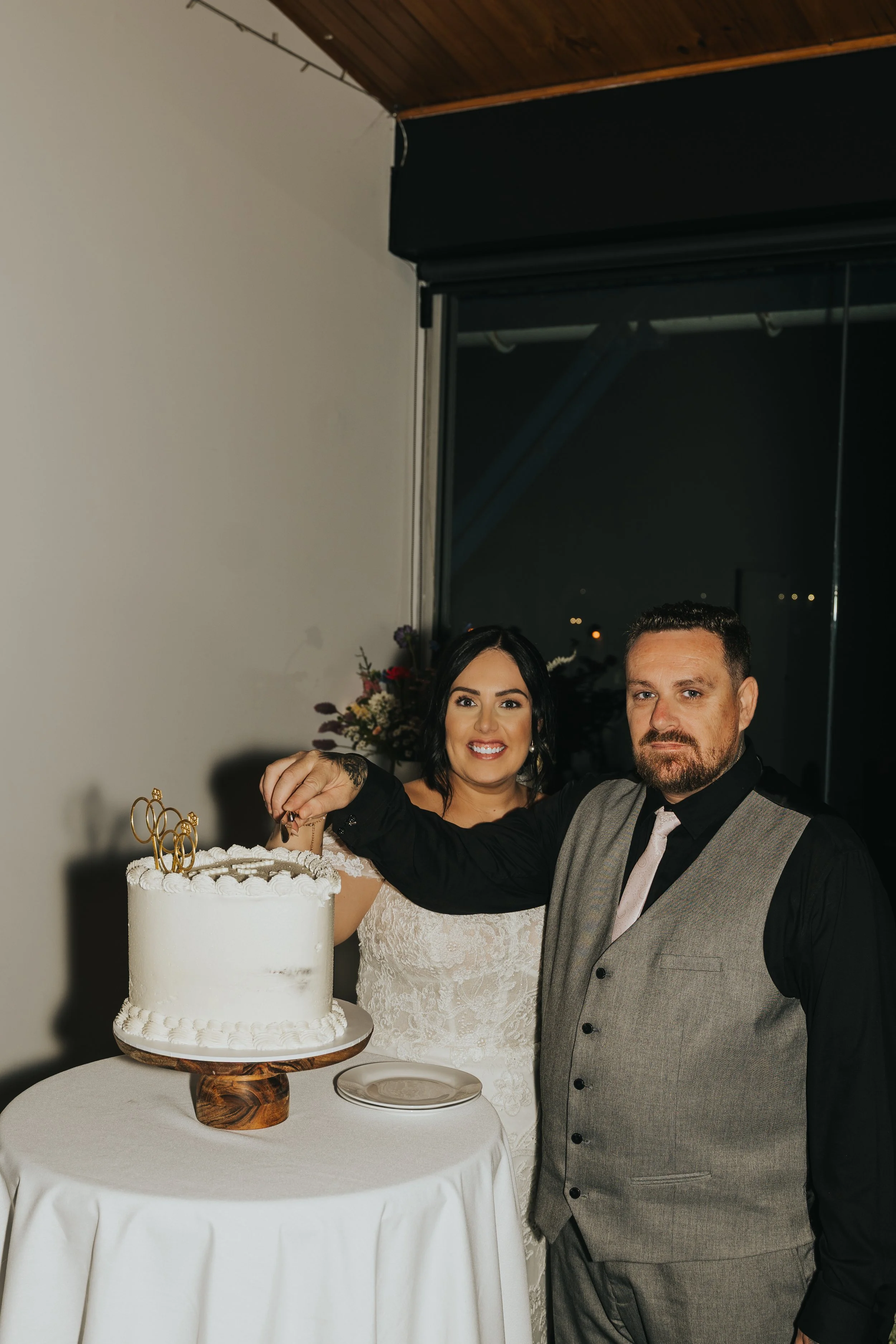 Happy bride and groom cutting wedding cake at reception.