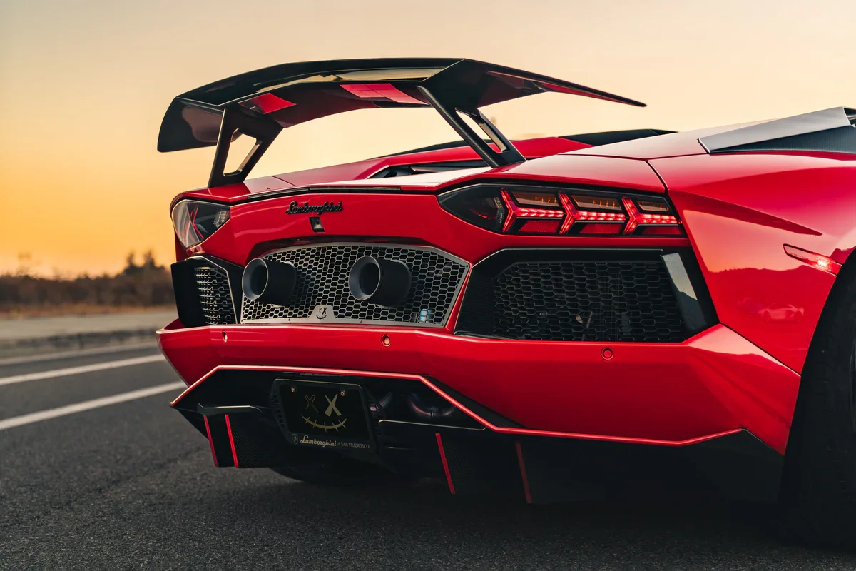 Red Lamborghini Aventador showcasing its aggressive rear diffuser, dual exhaust outlets, and dramatic rear wing — highlighting the bold aesthetic achievable through Voiture Noire's custom exhaust and performance styling services.